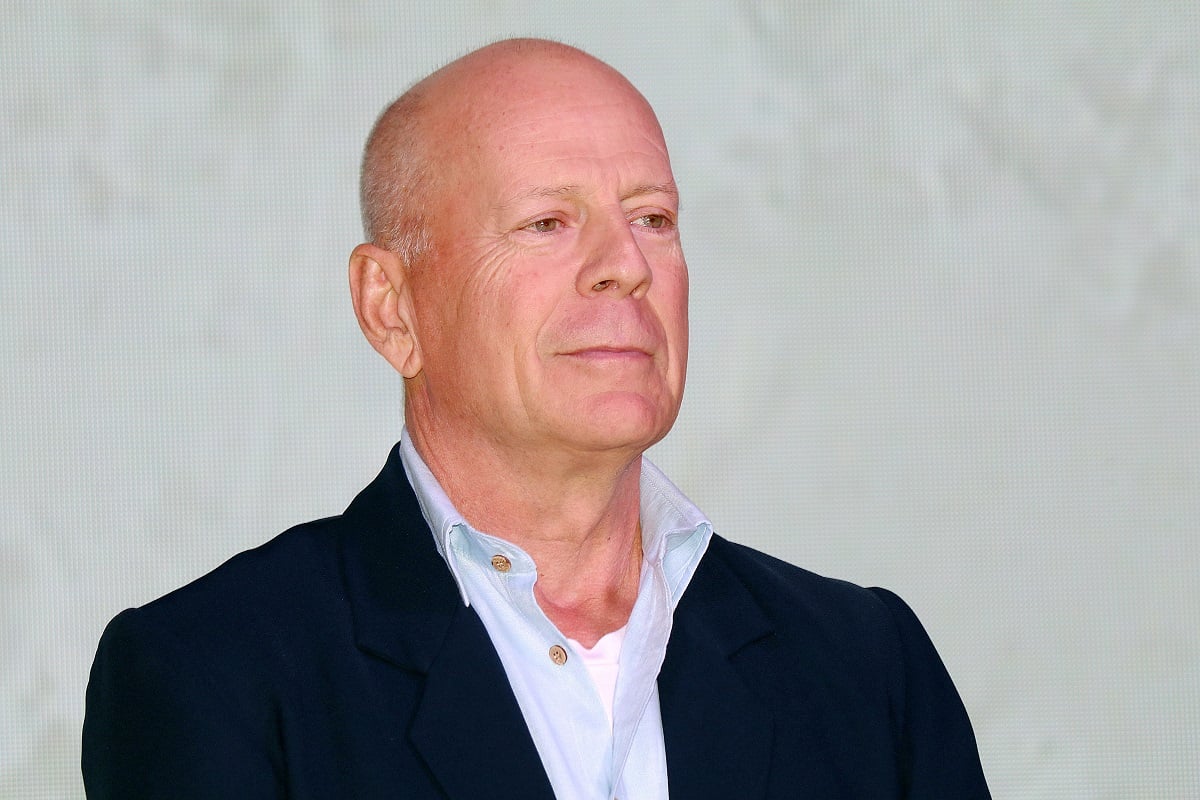 Bruce Willis smirking while wearing a suit.