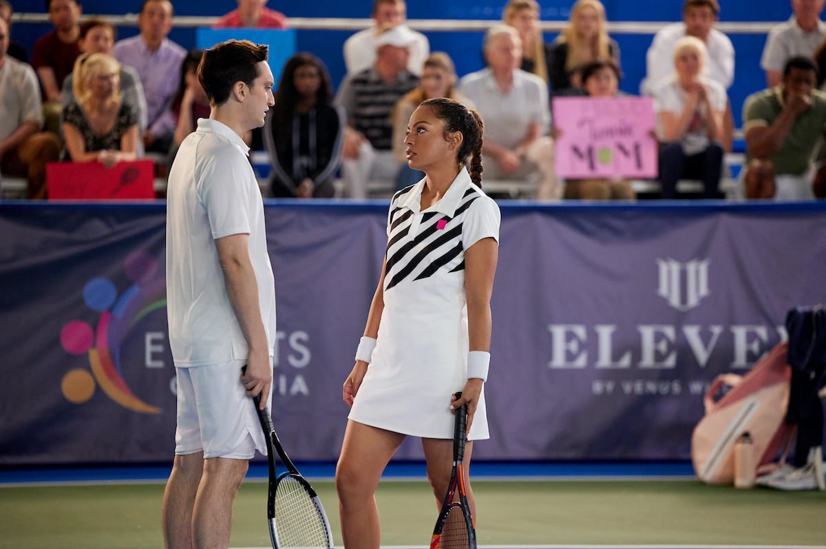 Richard Harmon and Davida Williams standing on a tennis court and looking at each other in Hallmark's 'Game, Set, Love'