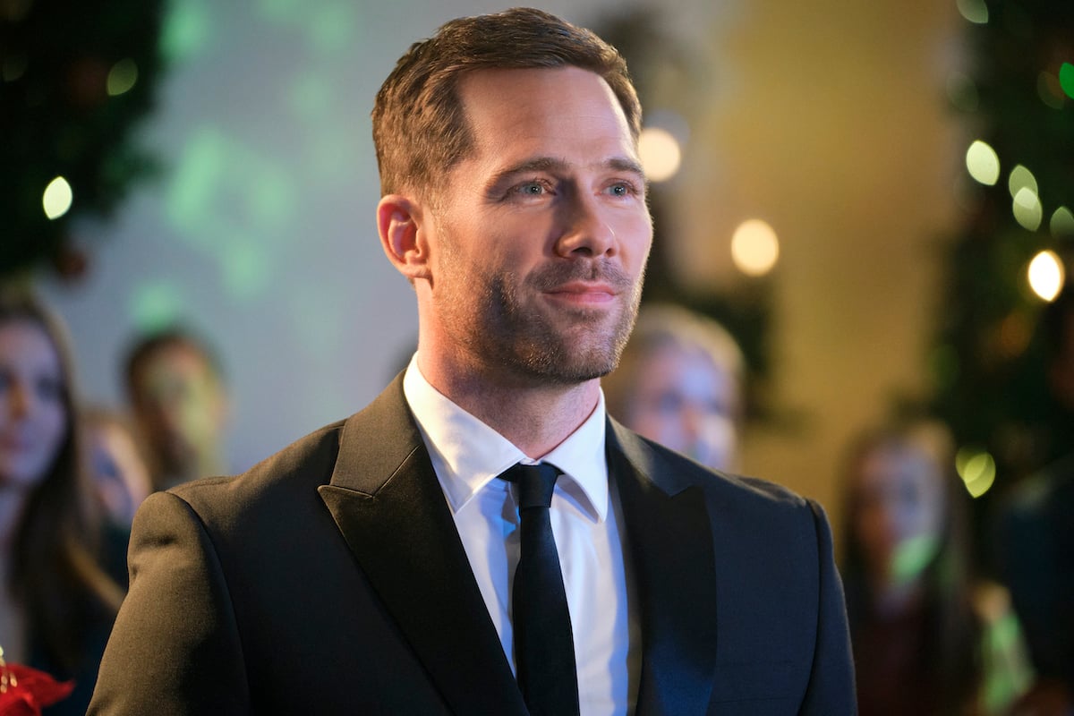 Luke Macfarlane, wearing a suit, in the Hallmark movie 'Chateau Christmas'