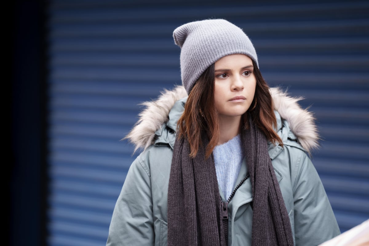 Selena Gomez as Mabel Mora in Only Murders in the Building Season 2. Mabel wears a coat with a fur hood, beanie, and scarf. 