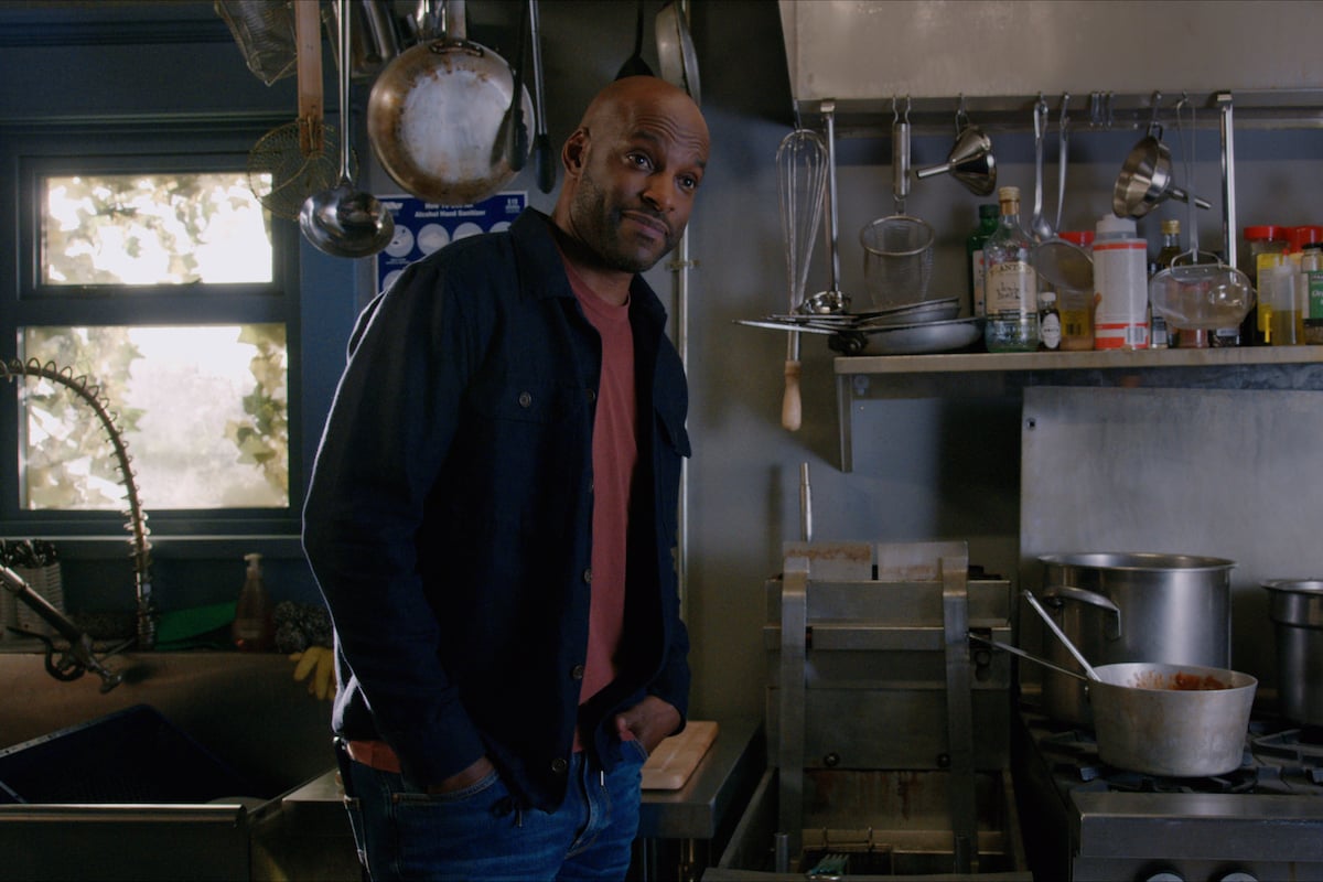 Colin Lawrence as Preacher wearing a blue jacket and standing in the kitchen in 'Virgin River