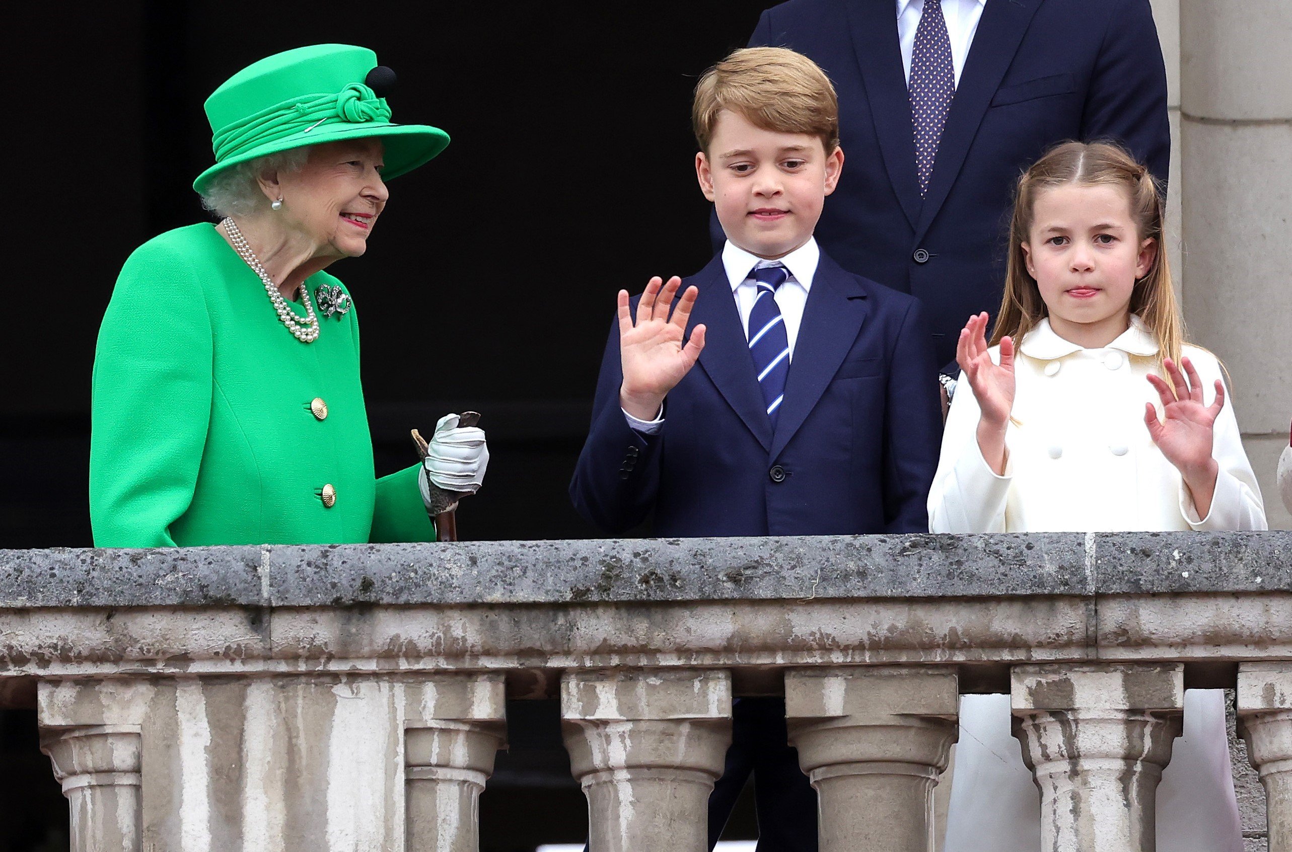 Queen Elizabeth II smiling at Prince George and Princess Charlotte, who uses the monarch as her body language role model,on the balcony of Buckingham Palace