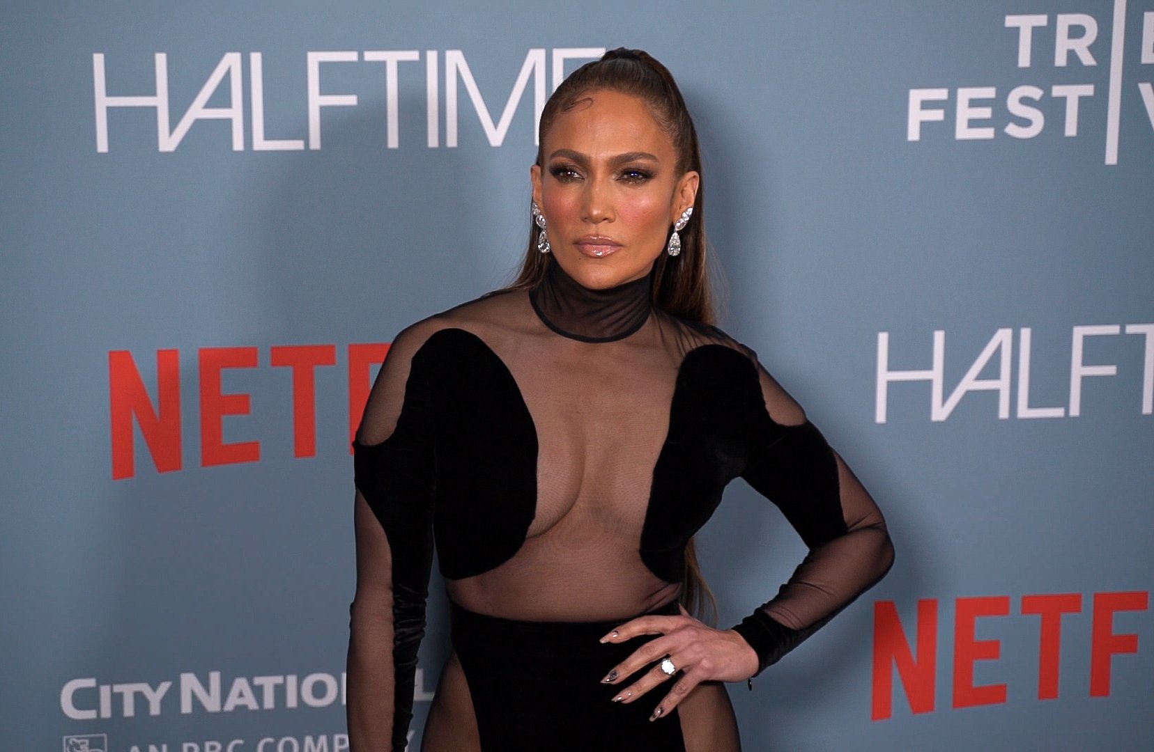 Jennifer Lopez poses in a black dress at the premiere for her documentary about the Super Bowl, Halftime.