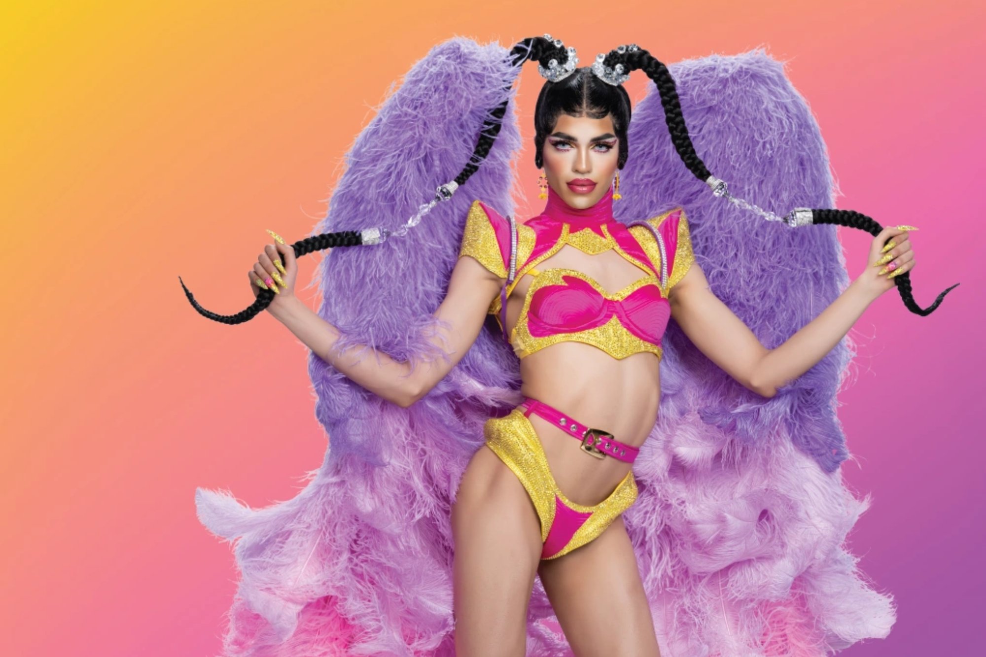'Canada's Drag Race' Miss Fiercalicious wearing a pink and yellow two-piece with large purple wings. She's holding her long ponytails out far from herself.