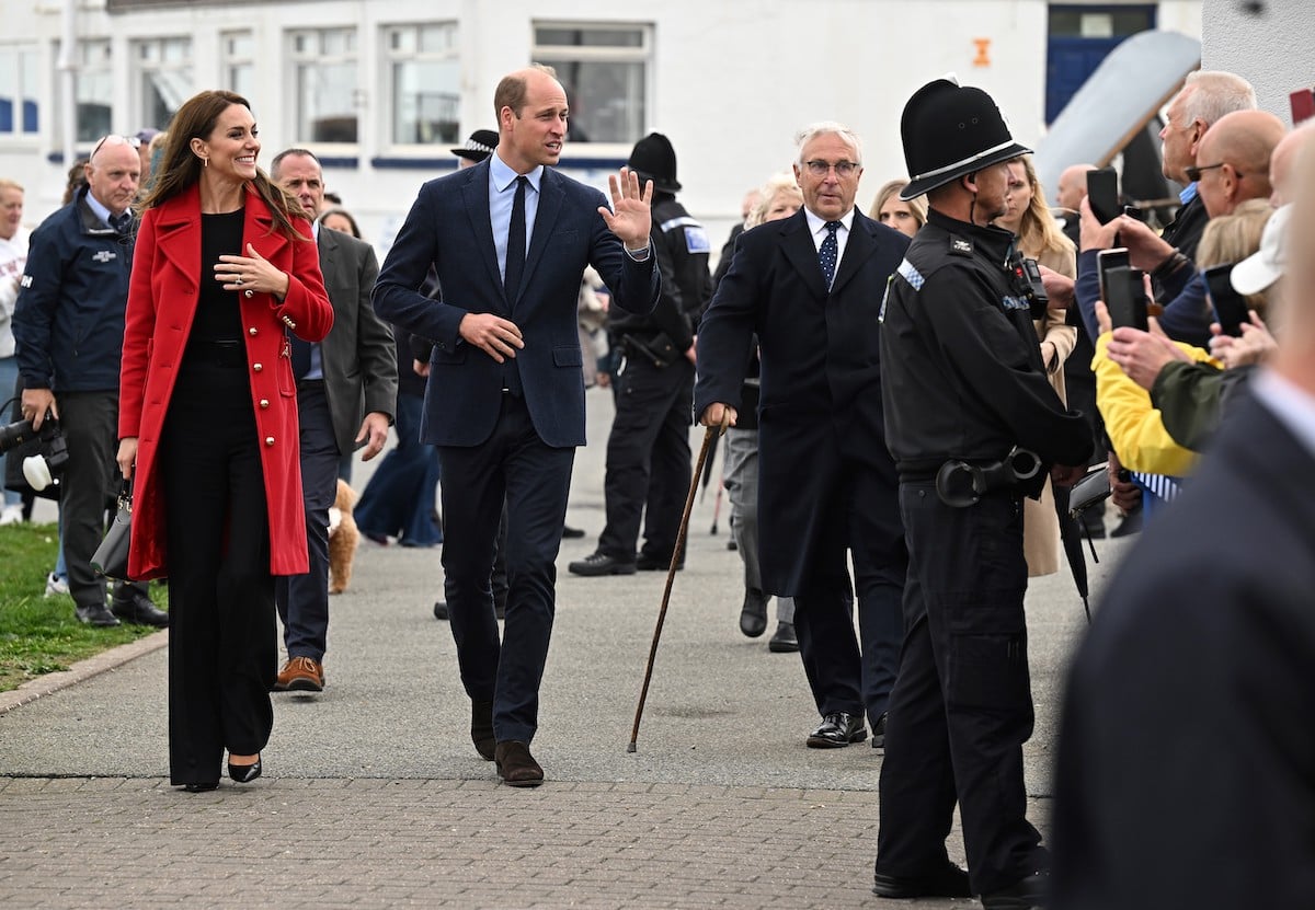 Kate Middleton and Prince William, who didn't have 'royal smiles' in Wales on Sept. 27, 2022, according to body language expert Judi James, walk past crowds 