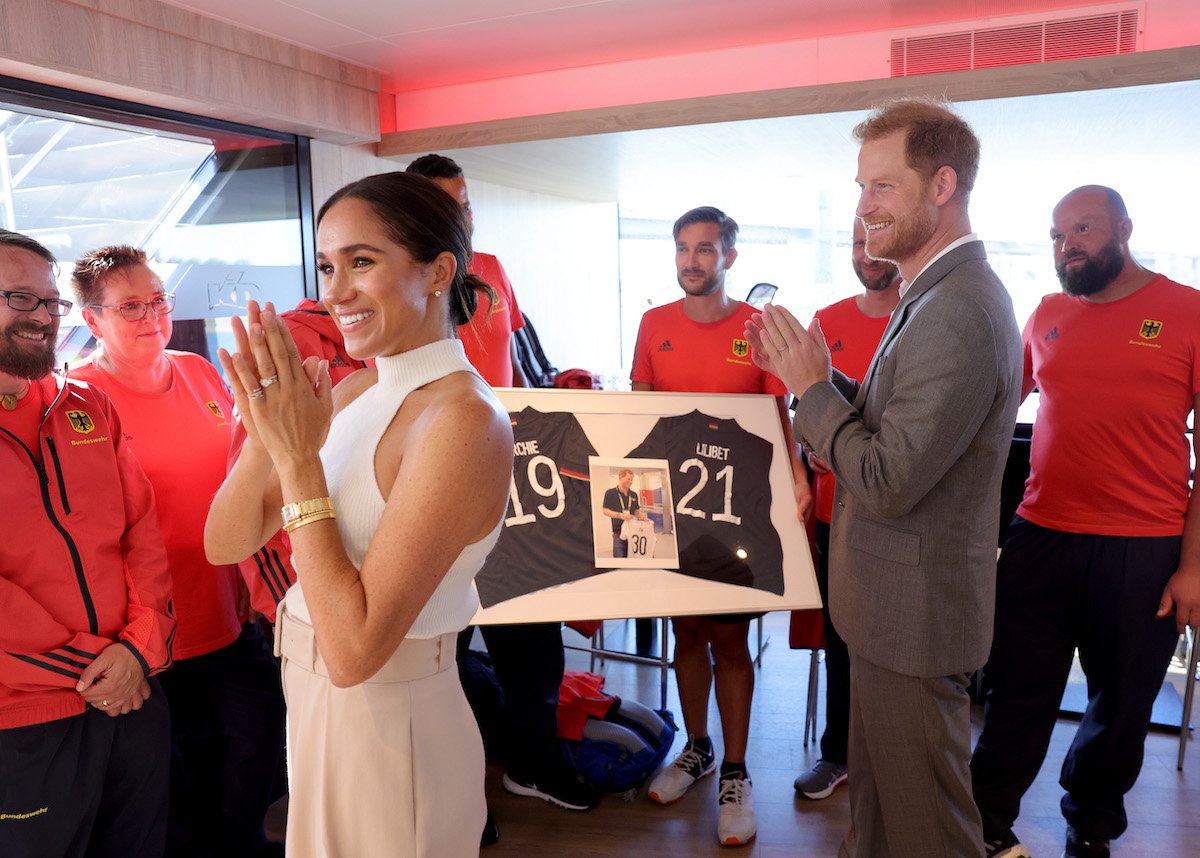 Meghan Markle and Prince Harry, who commentators say likely won't bring their children, Archie Harrison and Lilibet Diana, to Queen Elizabeth's funeral, clap