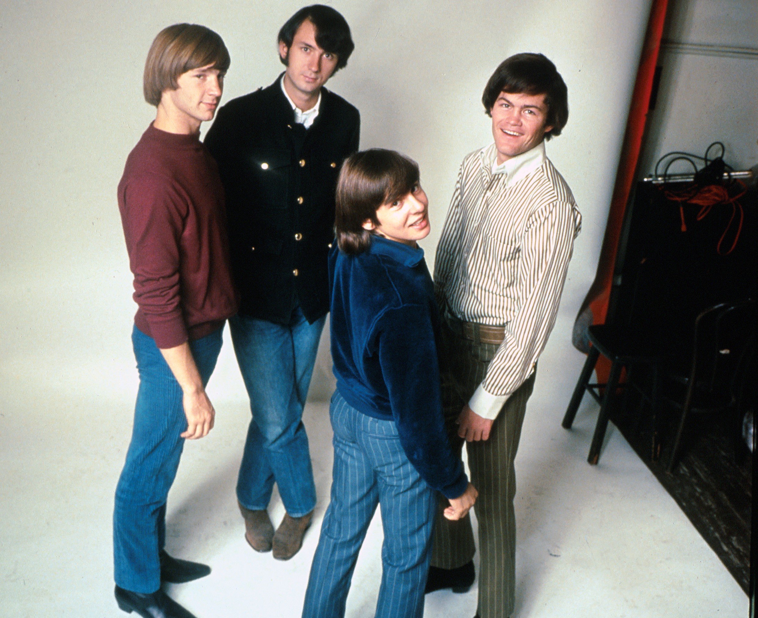 The Monkees' Peter Tork, Mike Nesmith, Davy Jones, and Micky Dolenz near chairs