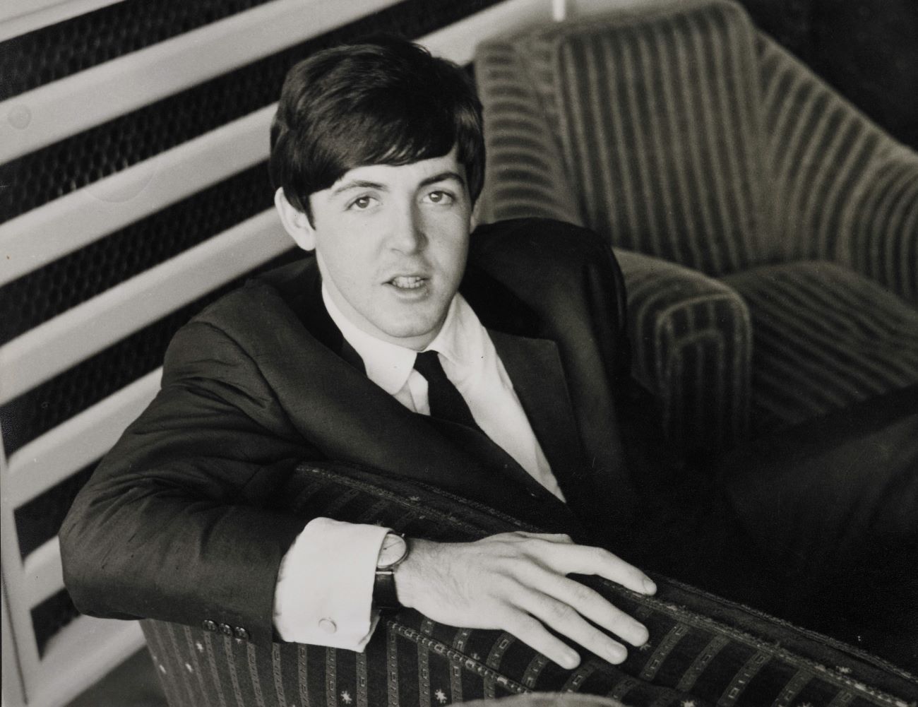 A black and white picture of Paul McCartney sitting in an armchair.