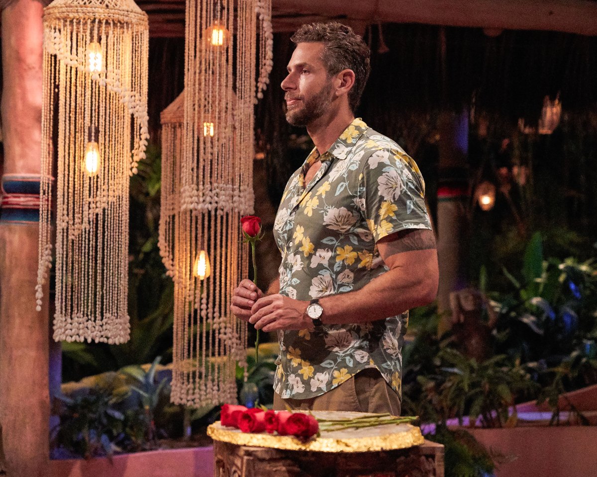 Casey Woods during the rose ceremony on Bachelor in Paradise Season 8. Casey wears a floral button-down shirt and holds a rose. 