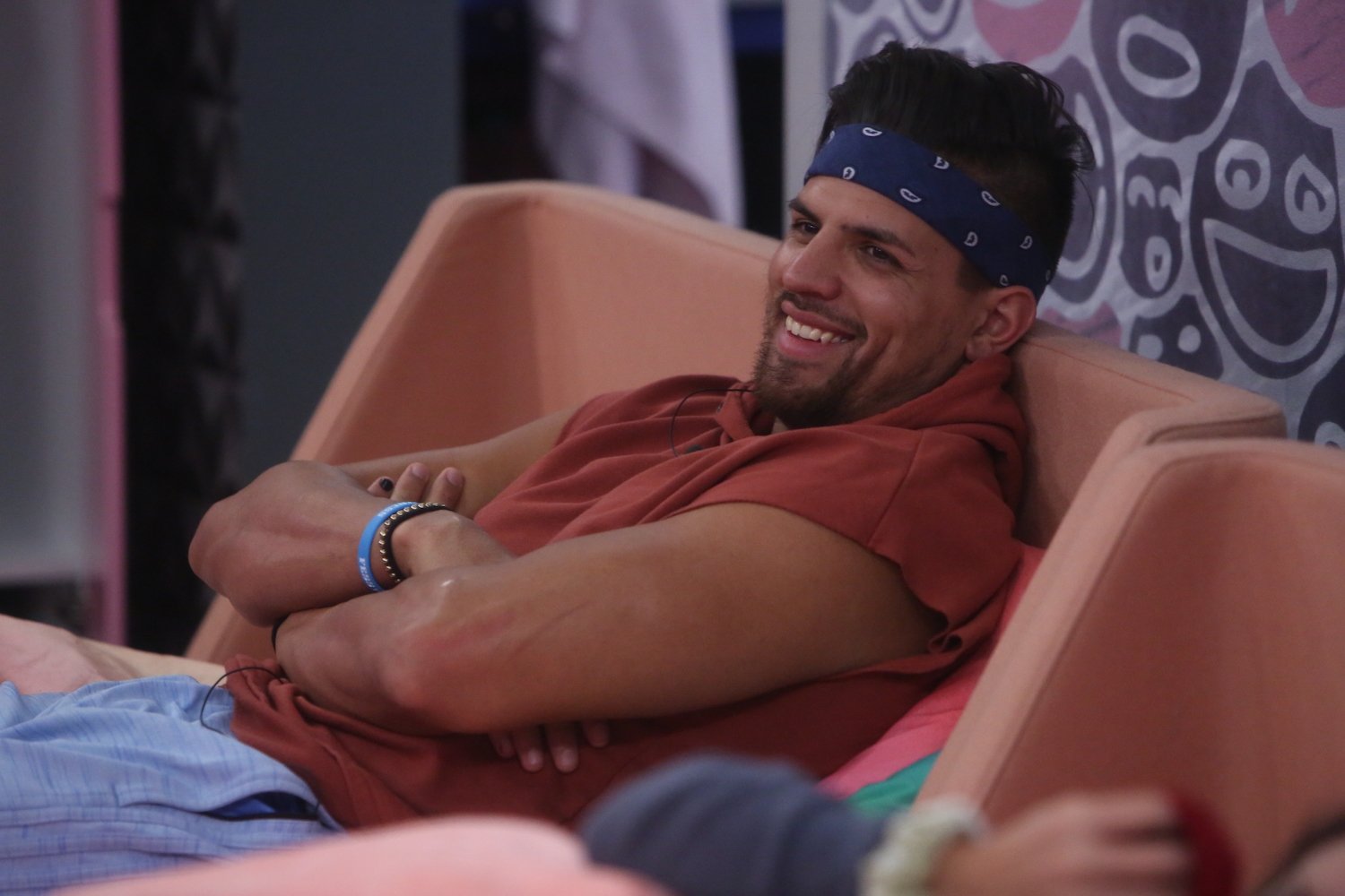 Fessy Shafaat from 'The Challenge' Season 38 smiling while lying on a couch in 'Big Brother'