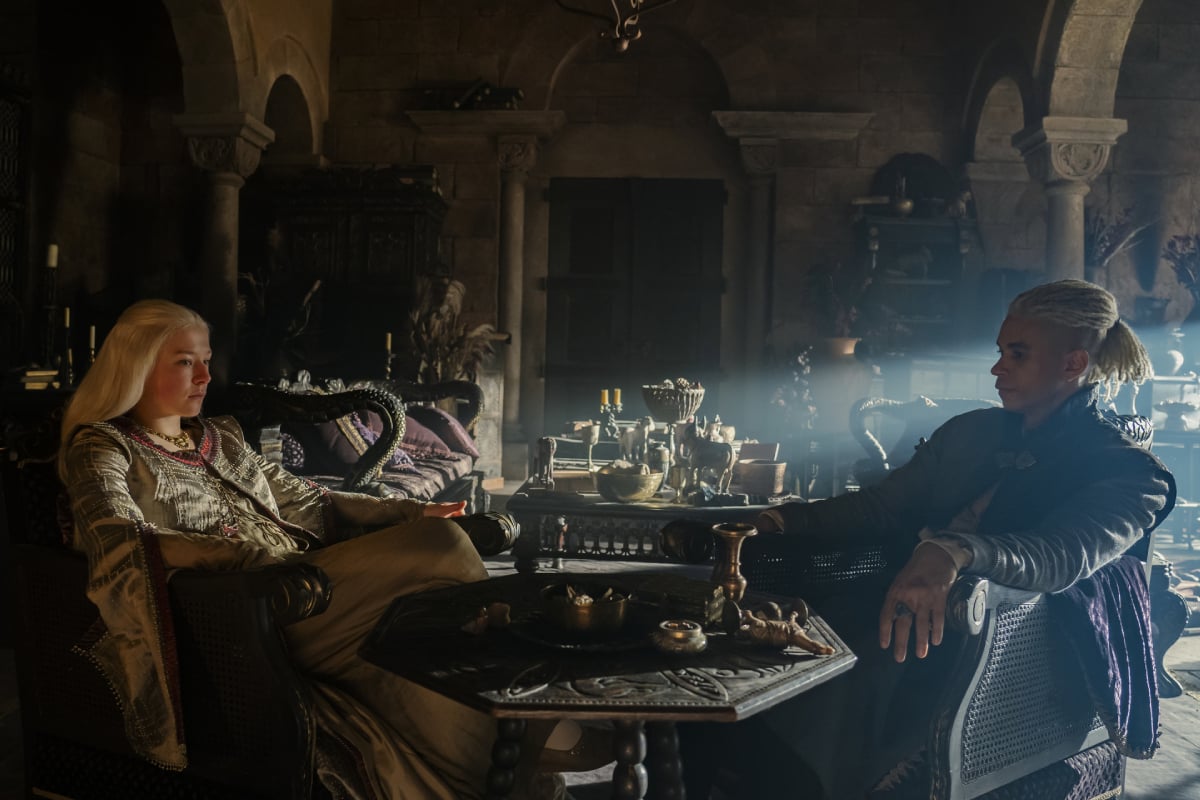 Emma D'Arcy as Rhaenyra and John Macmillan as Laenor in House of the Dragon. Laenor and Rhaenyra lounge in chairs with a table in front of them.