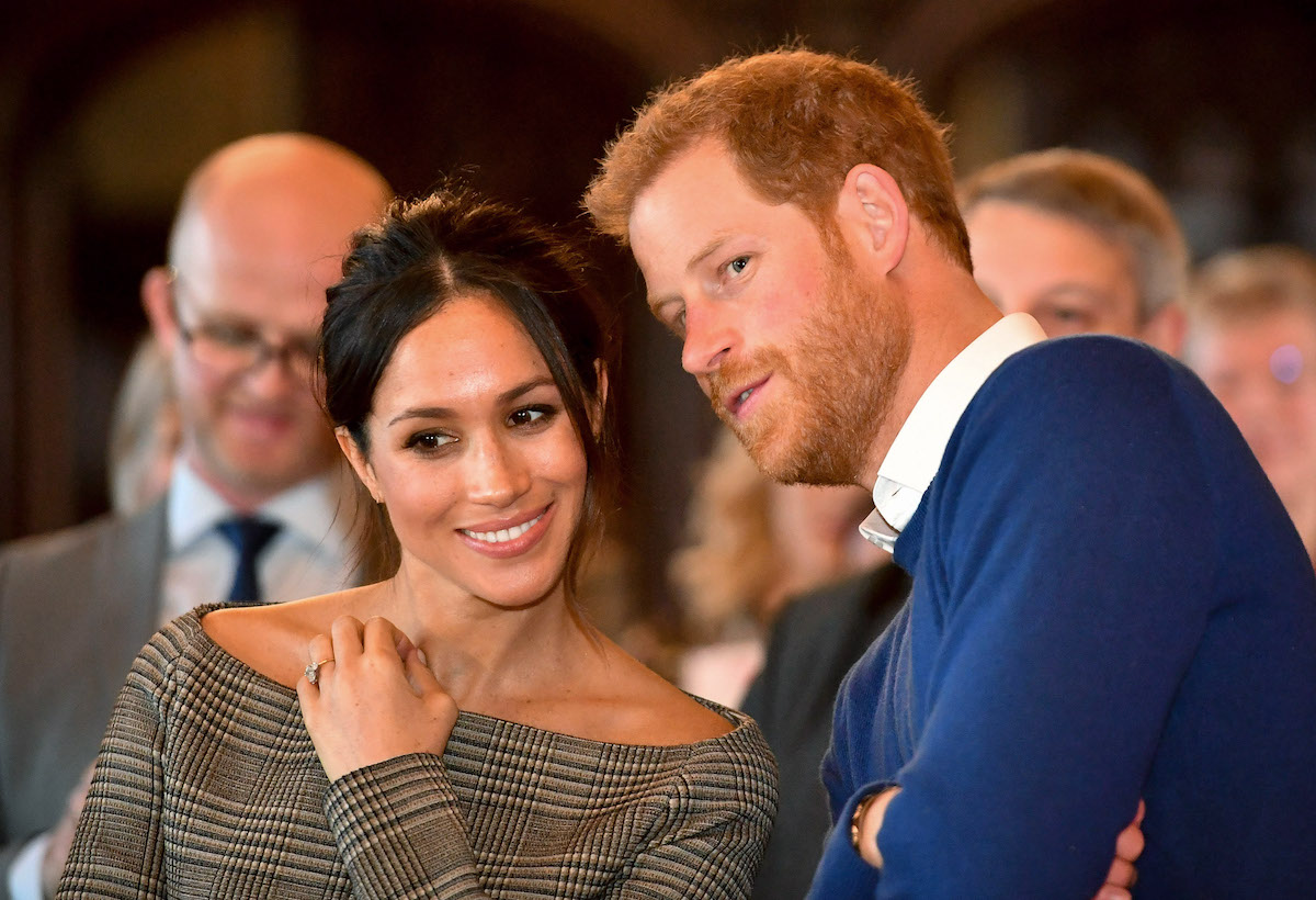 Prince Harry, who has his sentences finished by Meghan Markle, which is a good sign for their marriage according to a body language expert, whispers in Meghan Markle's ear in 2018