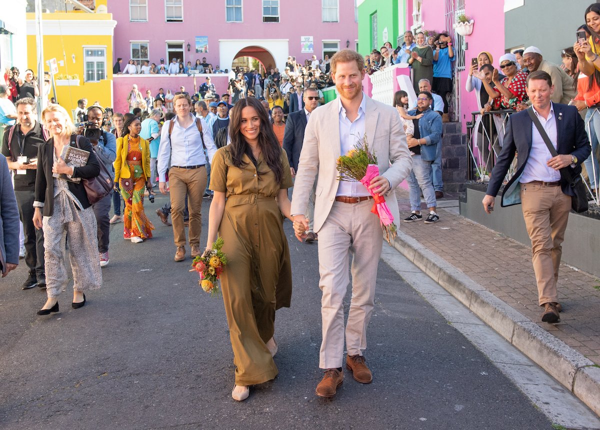 Meghan Markle, who was told to dress like Kate Middleton according to Katie Nicholl's 'The New Royals' book, wears a green dress in Cape Town, South Africa, as she walks with Prince Harry