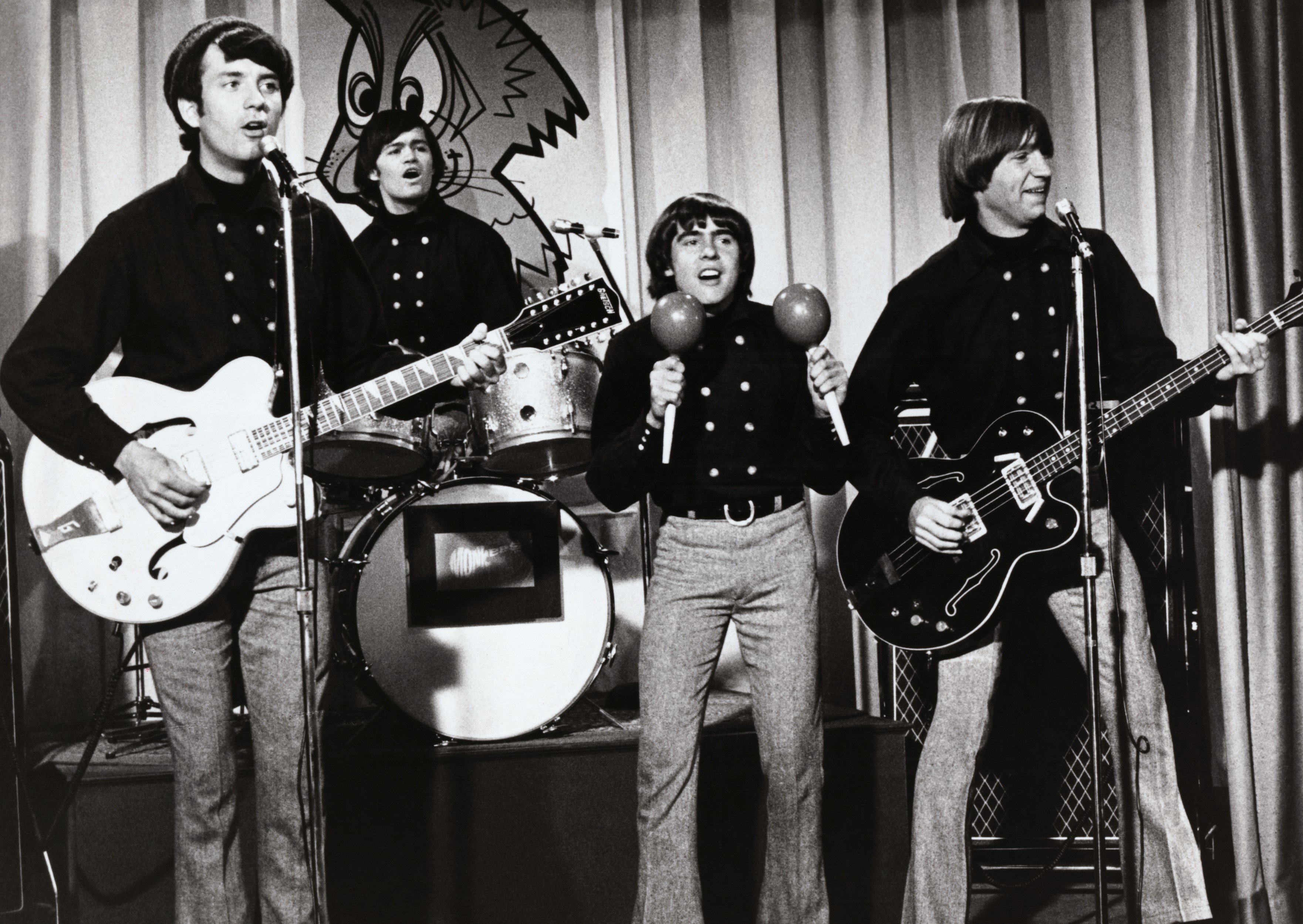 The Monkees' Mike Nesmith, Micky Dolenz, Davy Jones, and Peter Tork in front of a curtain