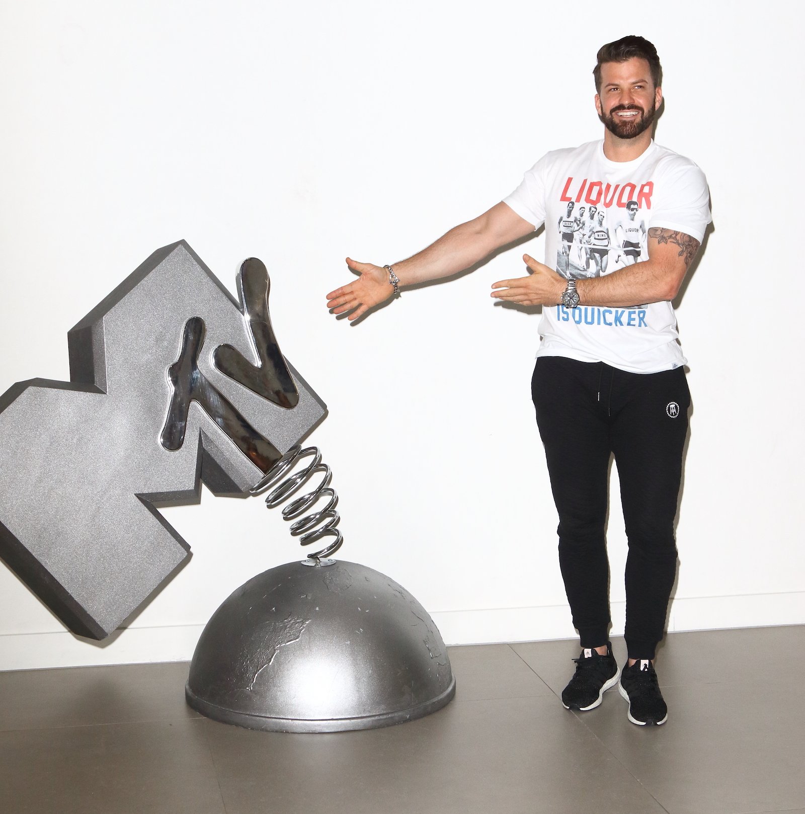 Johnny Bananas from 'The Challenge Ride or Dies' gestures toward a large statue of MTV