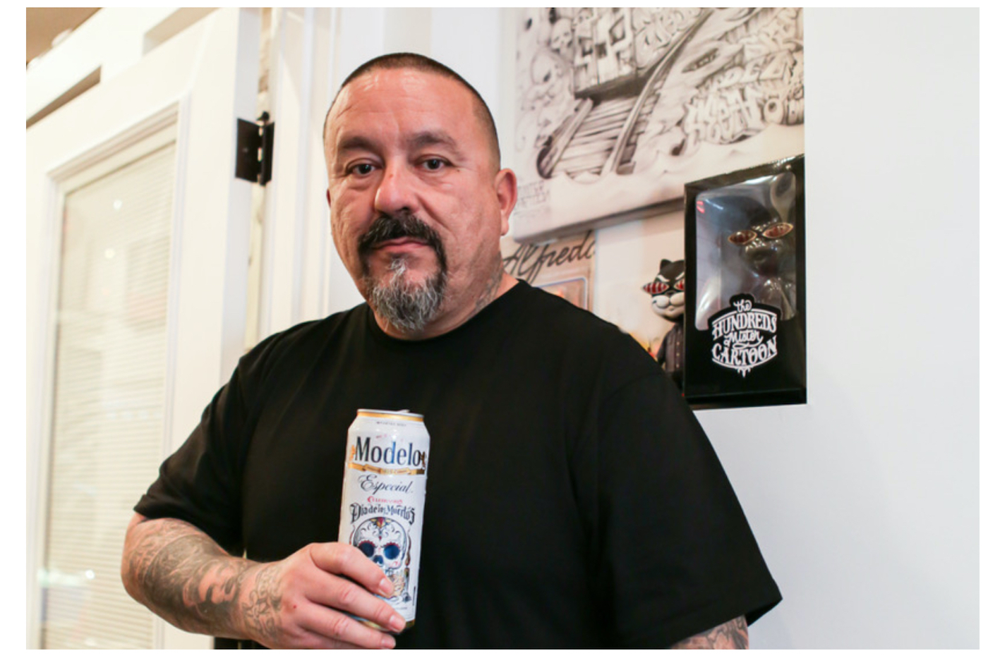 Tattoo artist Mister Cartoon holds a Modelo beer 