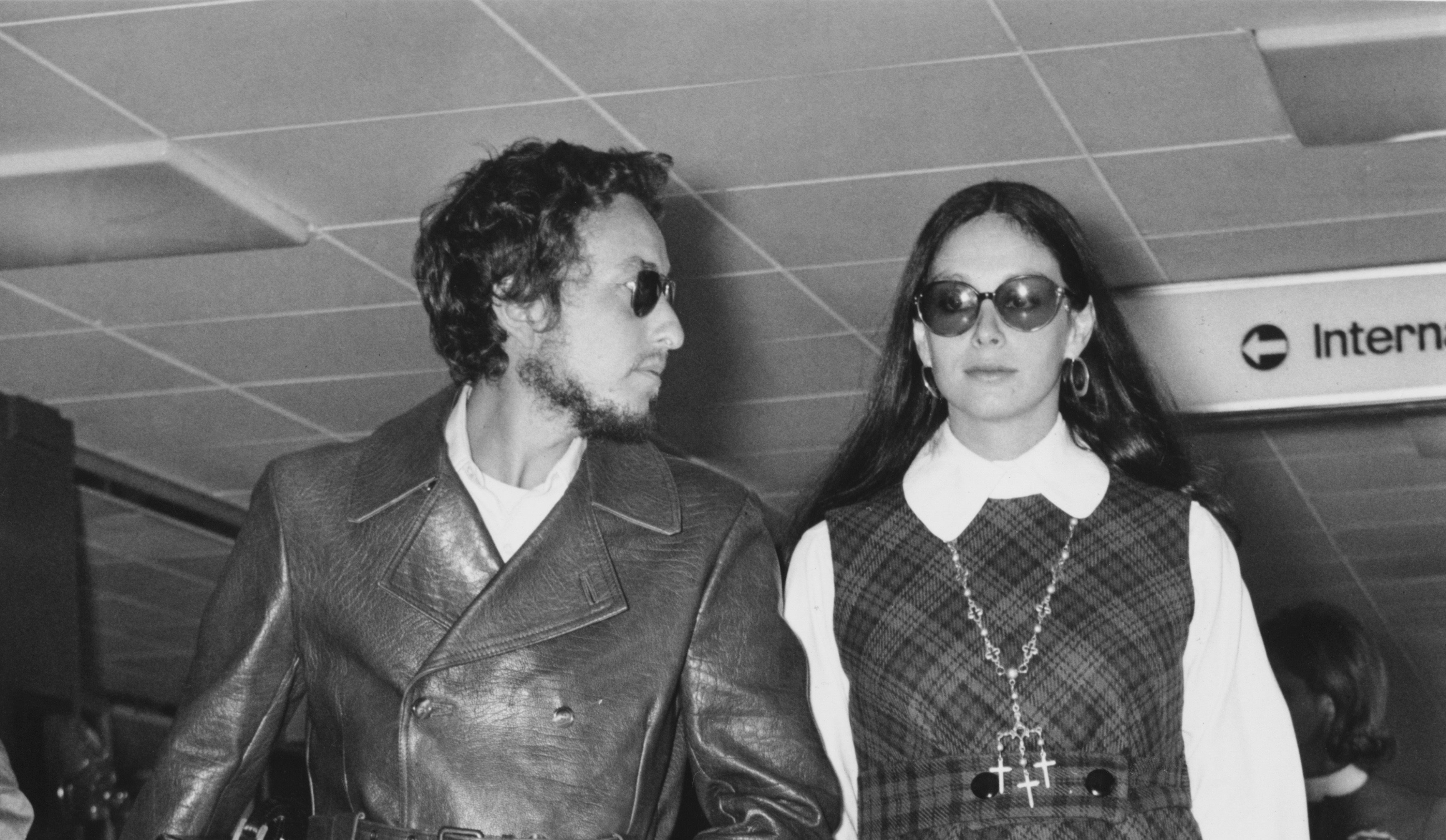 A black and white photo of Bob Dylan and his wife Sara Lownds walking together.