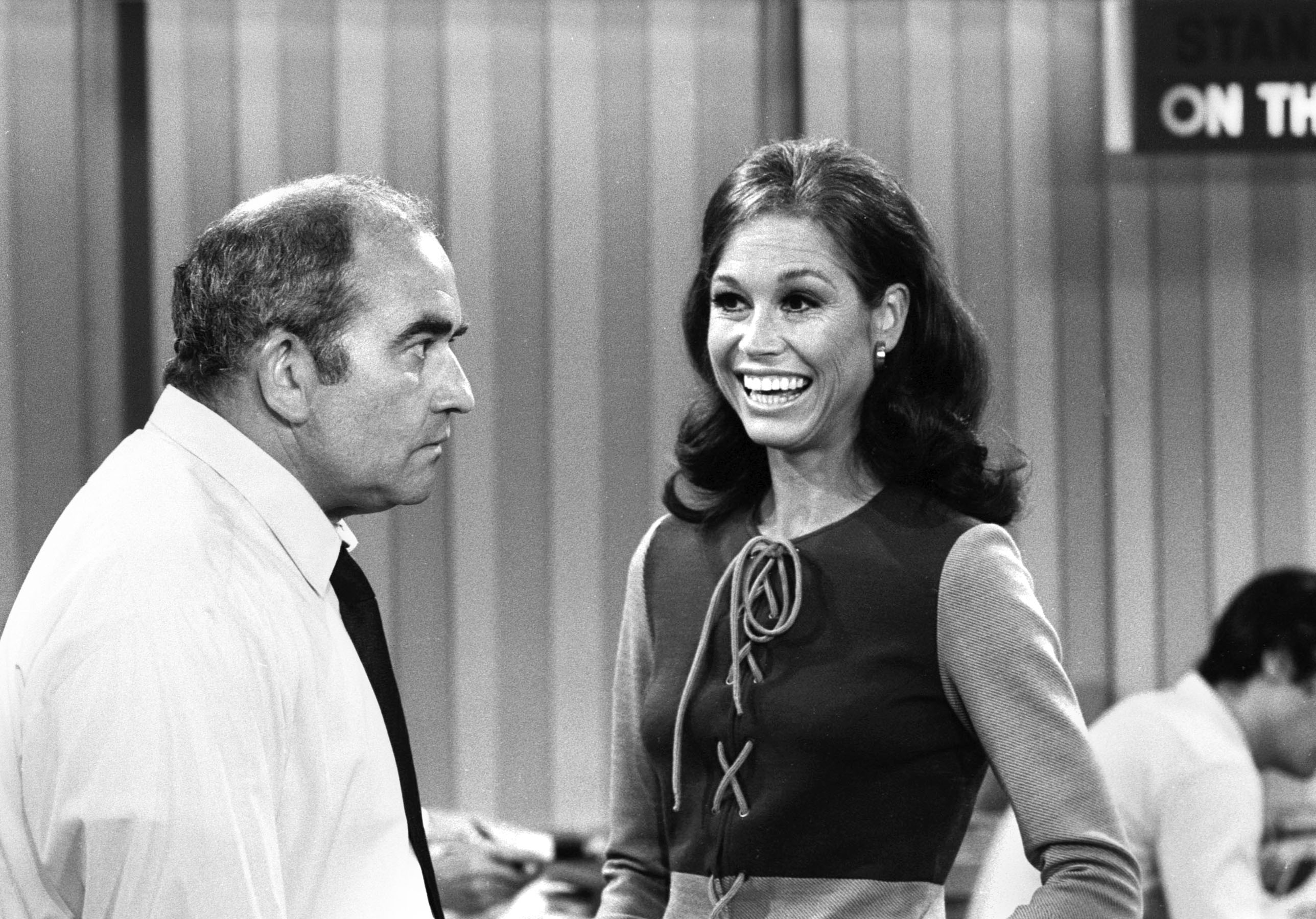 black and white image of Ed Asner looking at Mary Tyler Moore in 'The Mary Tyler Moore Show'