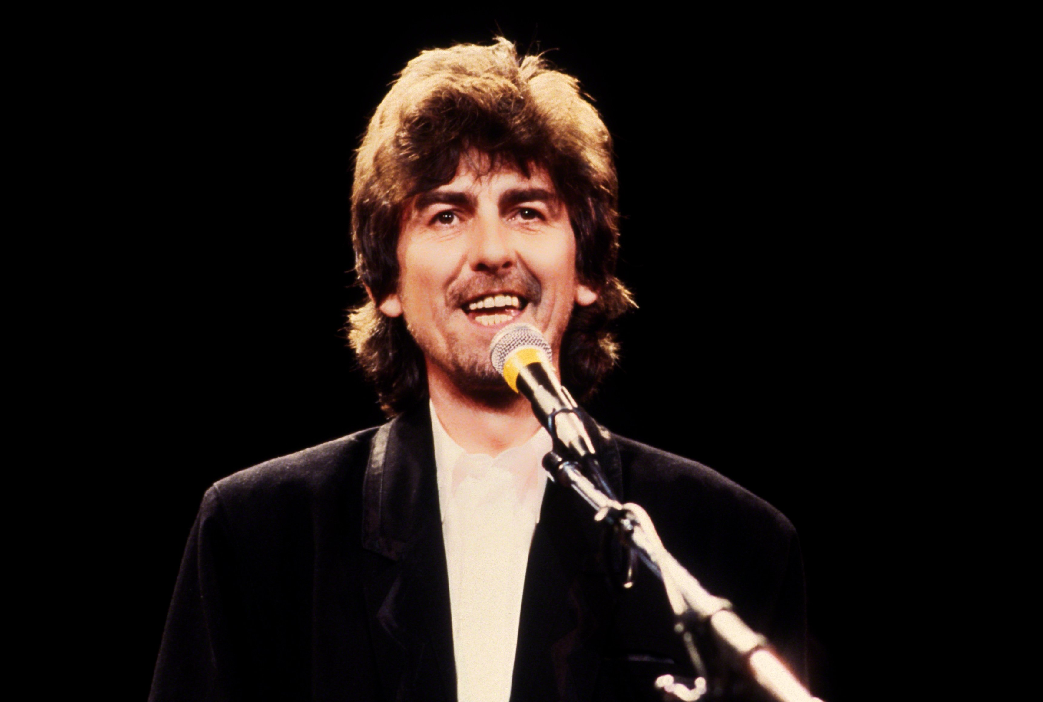 George Harrison with a microphone at The Beatles' Rock & Roll Hall of Fame induction