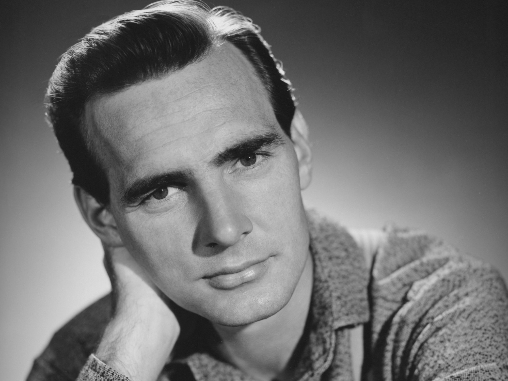 'Gunsmoke' Dennis Weaver in a black-and-white photo, resting his head on his hand.