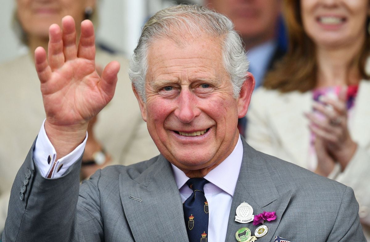 King Charles, whose body language shows he's a confident ruler, waves and smiles at an event.