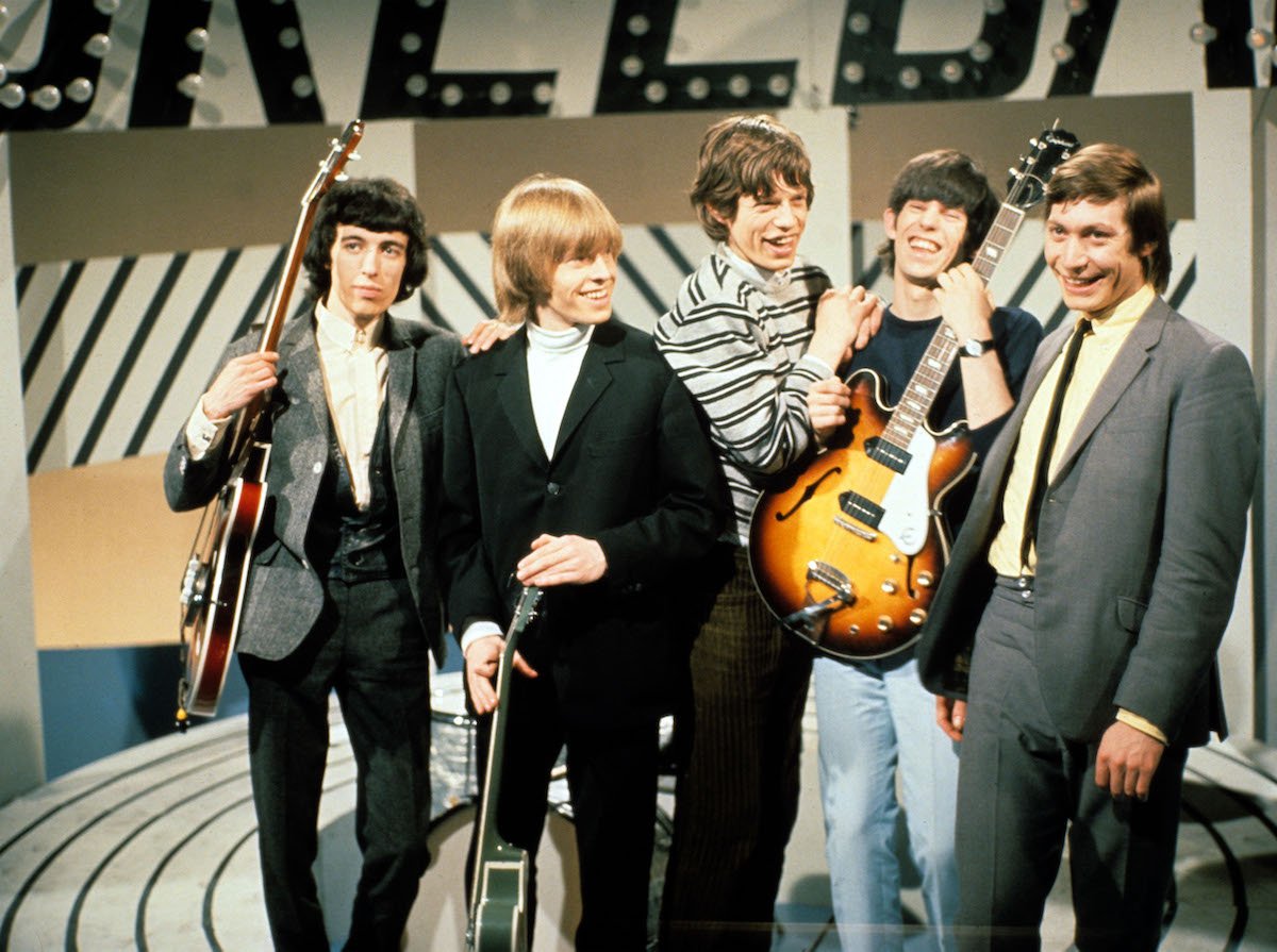 The Rolling Stones, Bill Wyman, Brian Jones, Mick Jagger, Keith Richards, and Charlie Watts, laugh during a TV taping in 1965