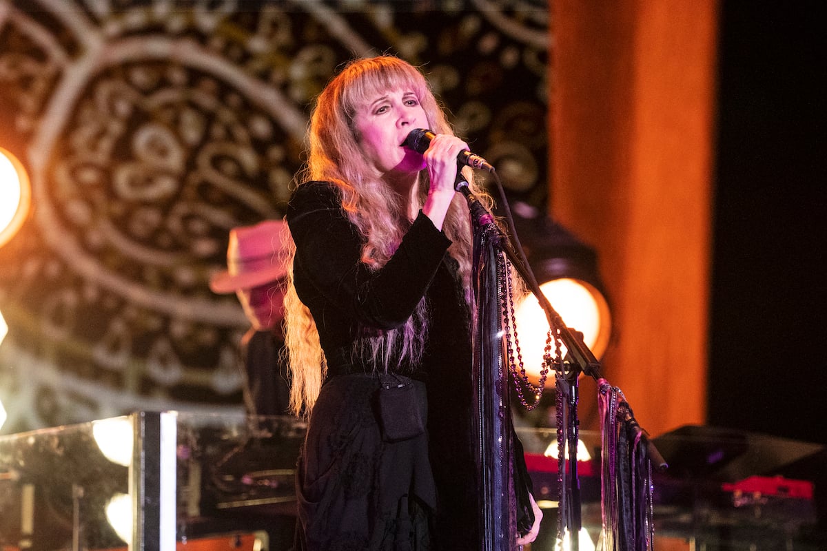 Stevie Nicks, who originally wanted to be an R&B singer, sings into a microphone on stage.