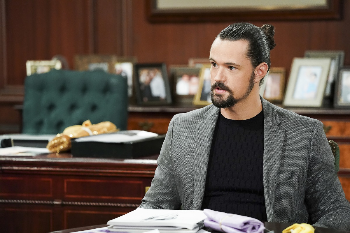 'The Bold and the Beautiful' star Matthew Atkinson in a grey suit and black shirt, sitting at a desk.