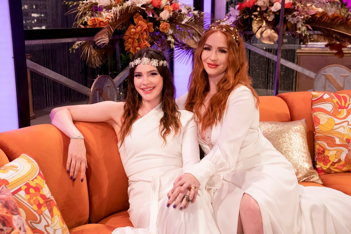 'The Young and the Restless' stars Cait Fairbanks and Camryn Grimes wearing wedding dresses and sitting on a couch.