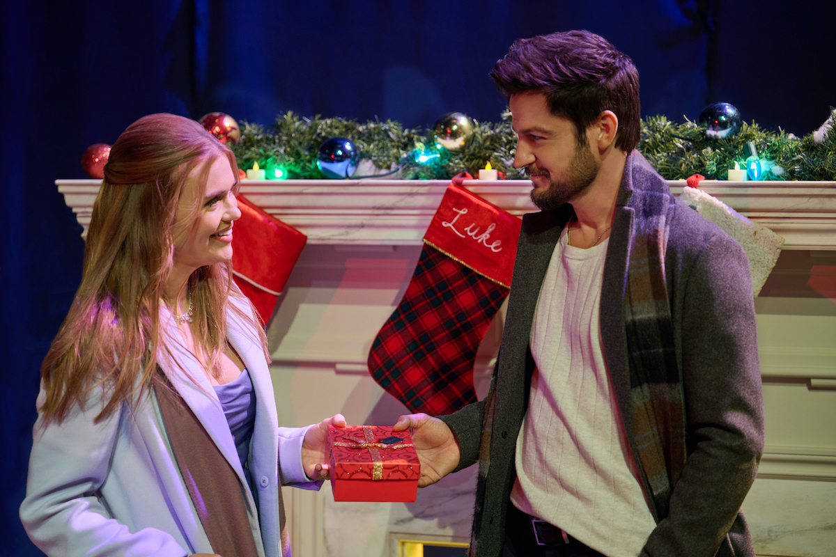 Holland Roden and Tyler Hynes standing in front of a decorated mantle in 'Time for Him to Come Home for Christmas'