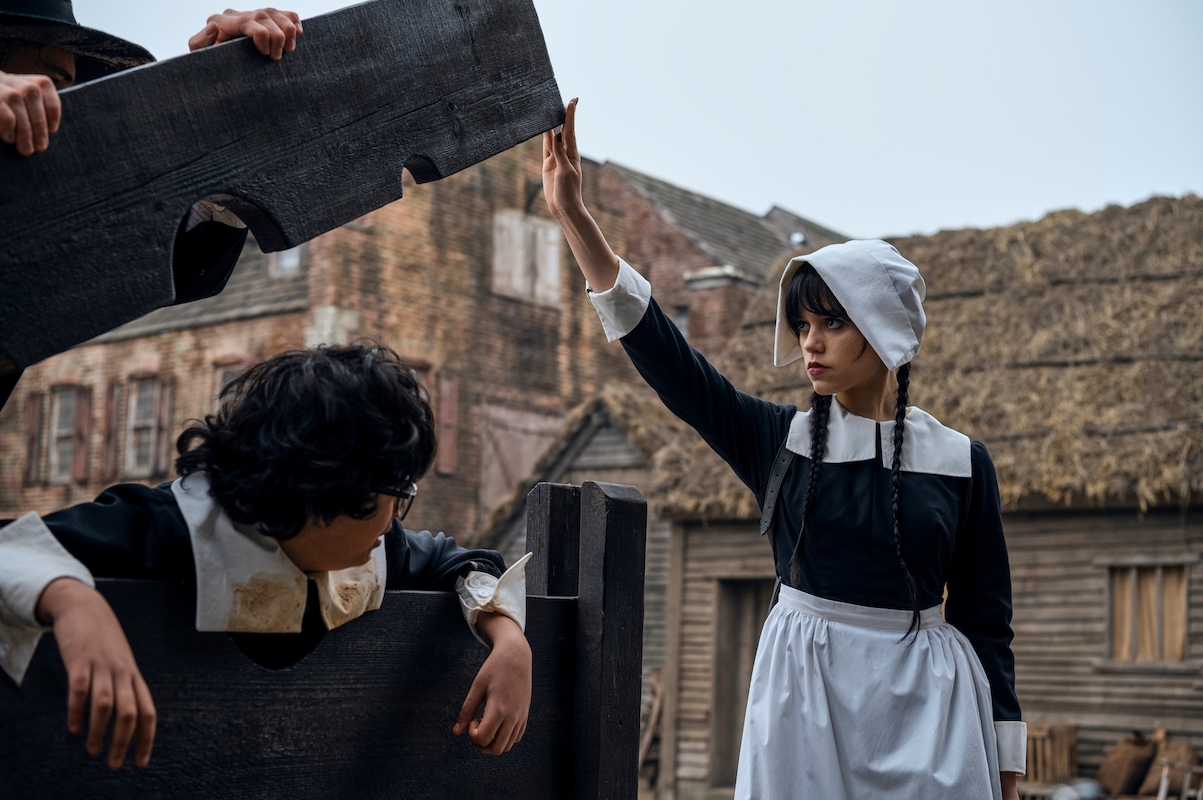 Wednesday Addams (Jenna Ortega) frees Eugene (Moosa Mostafa) from the stocks.