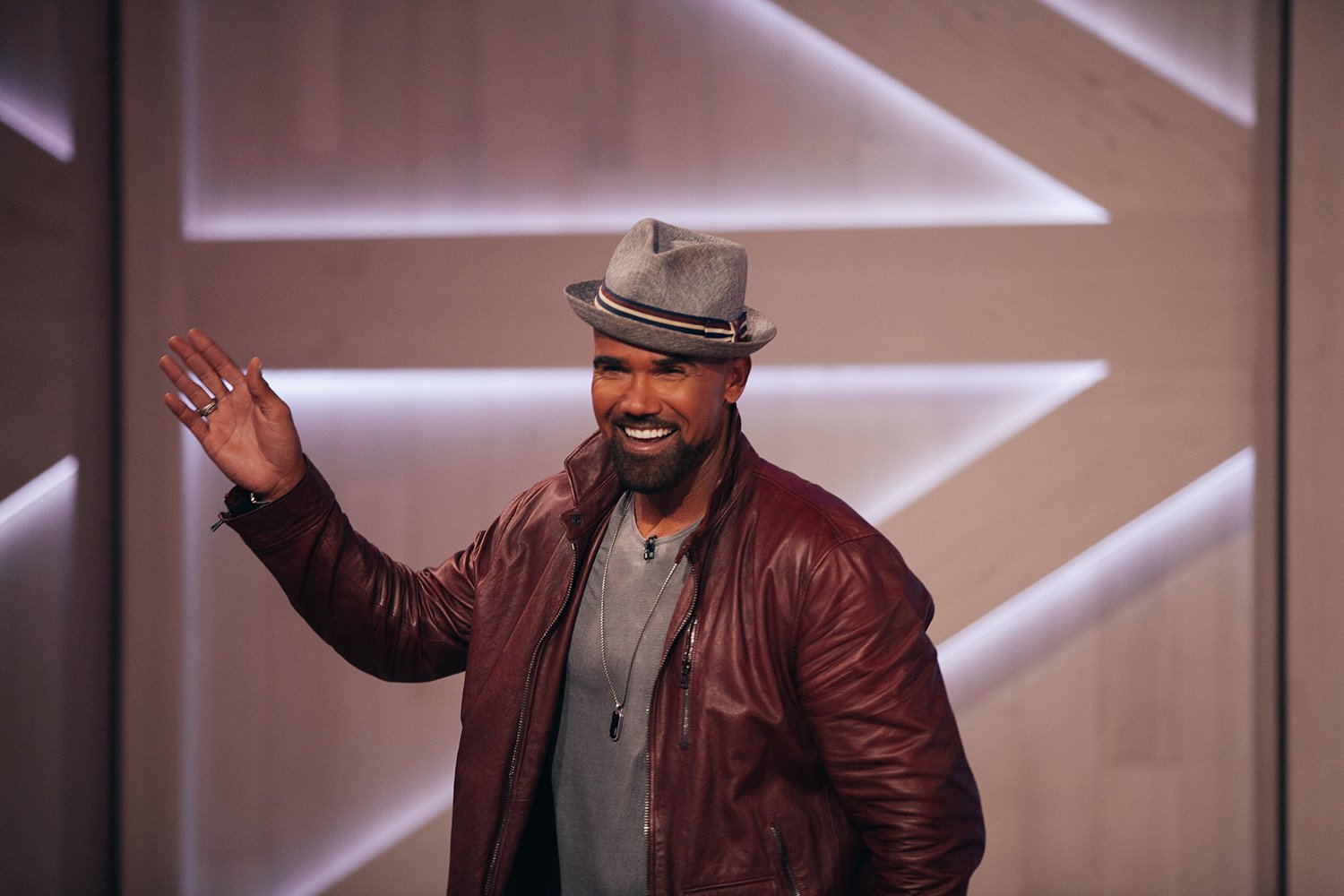 ‘Criminal Minds’ star Shemar Moore waving while wearing a red jacket and grety hat on ‘The Kelly Clarkson Show’
