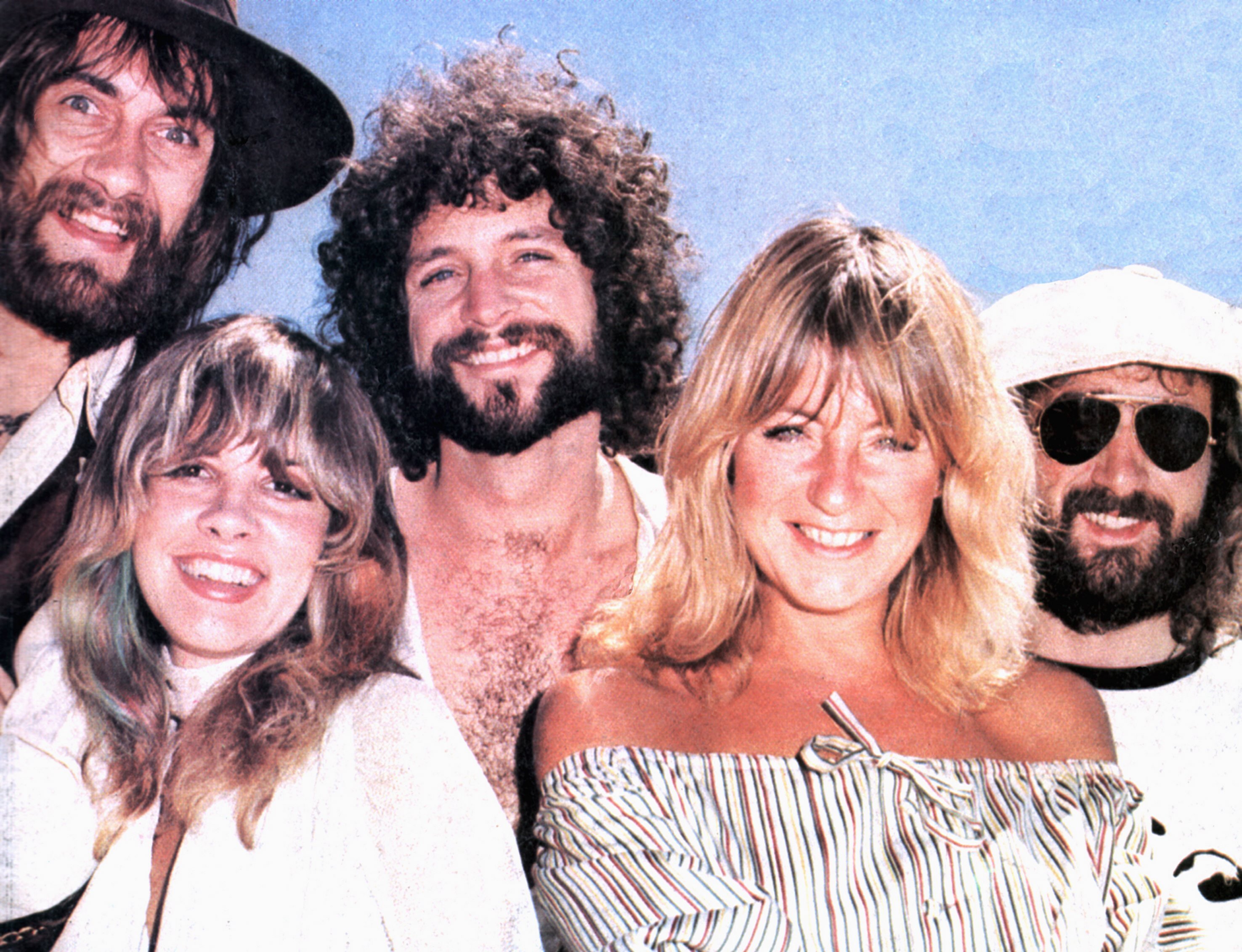 Mick Fleetwood, Stevie Nicks, Lindsey Buckingham, Christine McVie, and John McVie of Fleetwood Mac pose against a blue background.