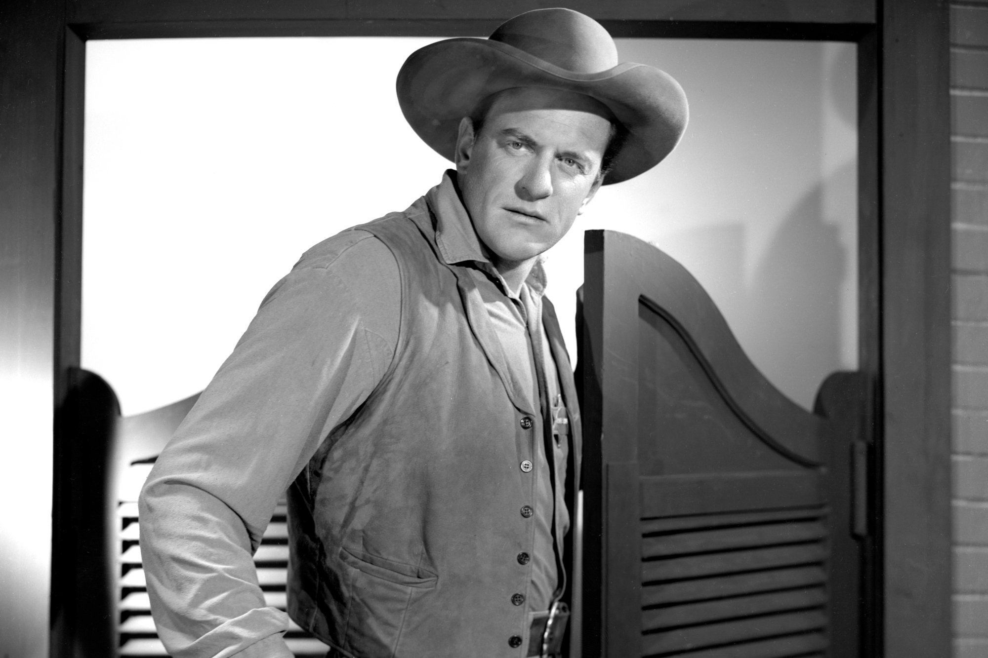 'Gunsmoke' James Arness as U.S. Marshal Matt Dillon in a black-and-white picture wearing a Western uniform in front of swinging doors