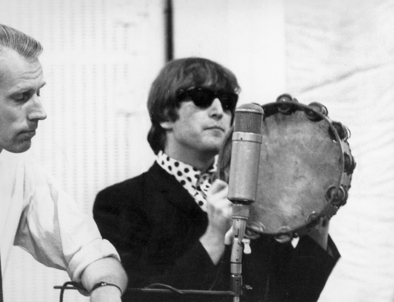 John Lennon in the recording studio with The Beatles' producer, George Martin, in 1964.