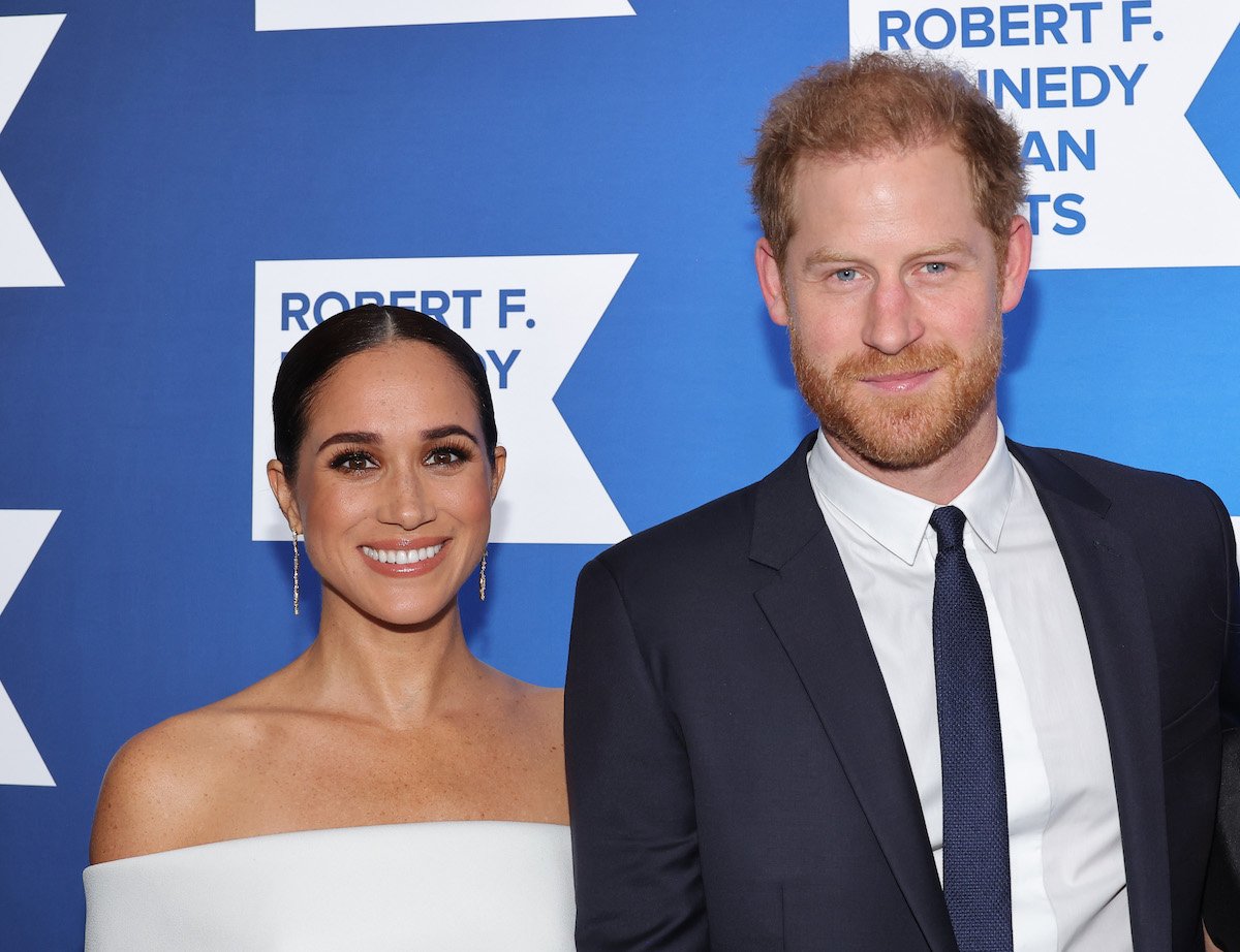 Meghan Markle and Prince Harry, who is releasing a book in 2023, smile and pose together at an event.