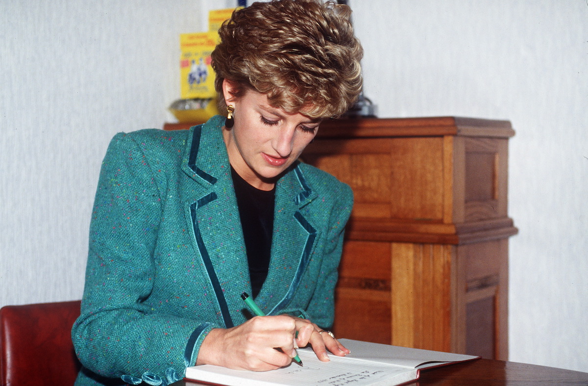 Princess Diana, who appeared 'photoshopped' in a 1986 Christmas card, according to a body language expert, signs a visitors book