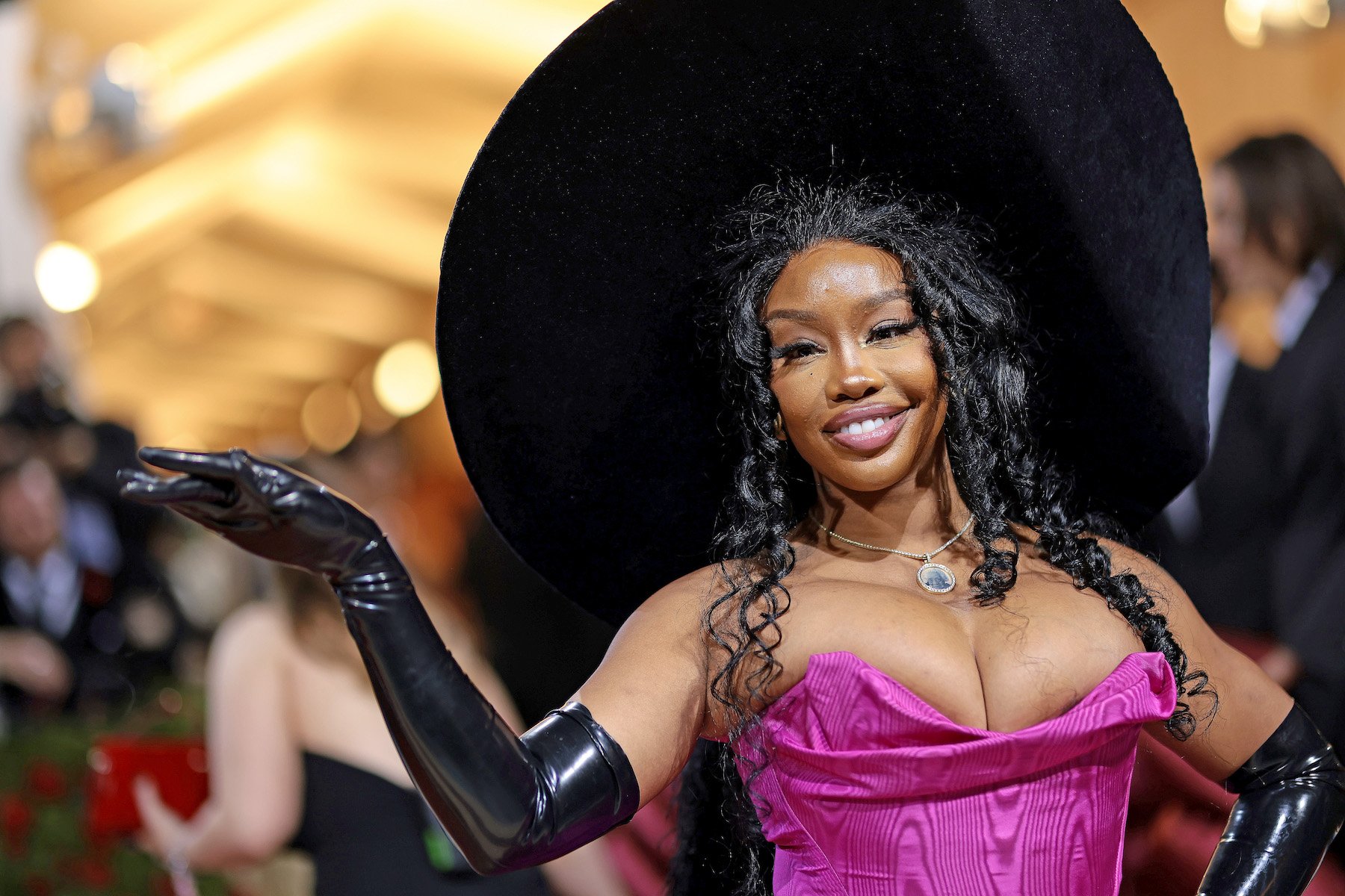 SZA, who's going on tour in 2023 to promote her album 'SOS,' searing a pink dress and a black hat