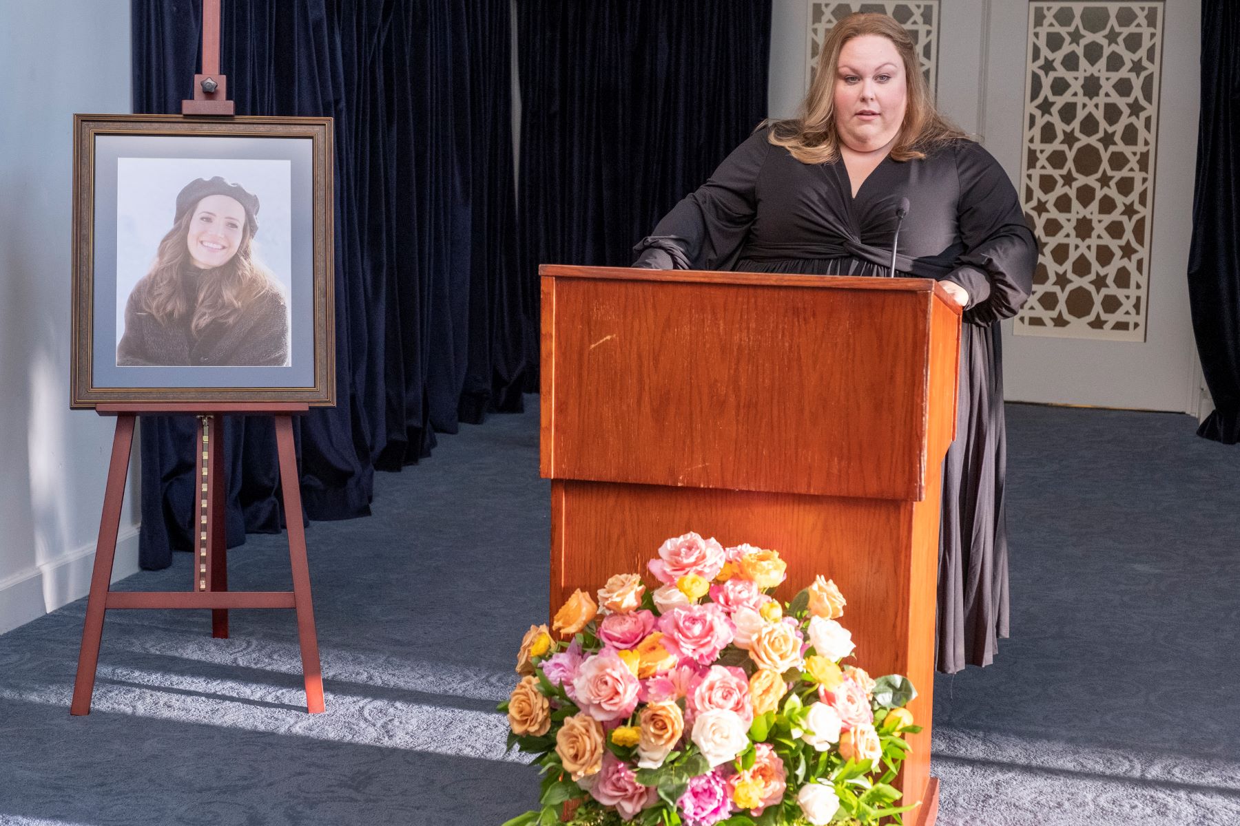 Chrissy Metz, in character as Kate Pearson in 'This Is Us' Season 6 Episode 18, one of the several series finales in 2022, wears a black dress while giving a speech at Rebecca's funeral.