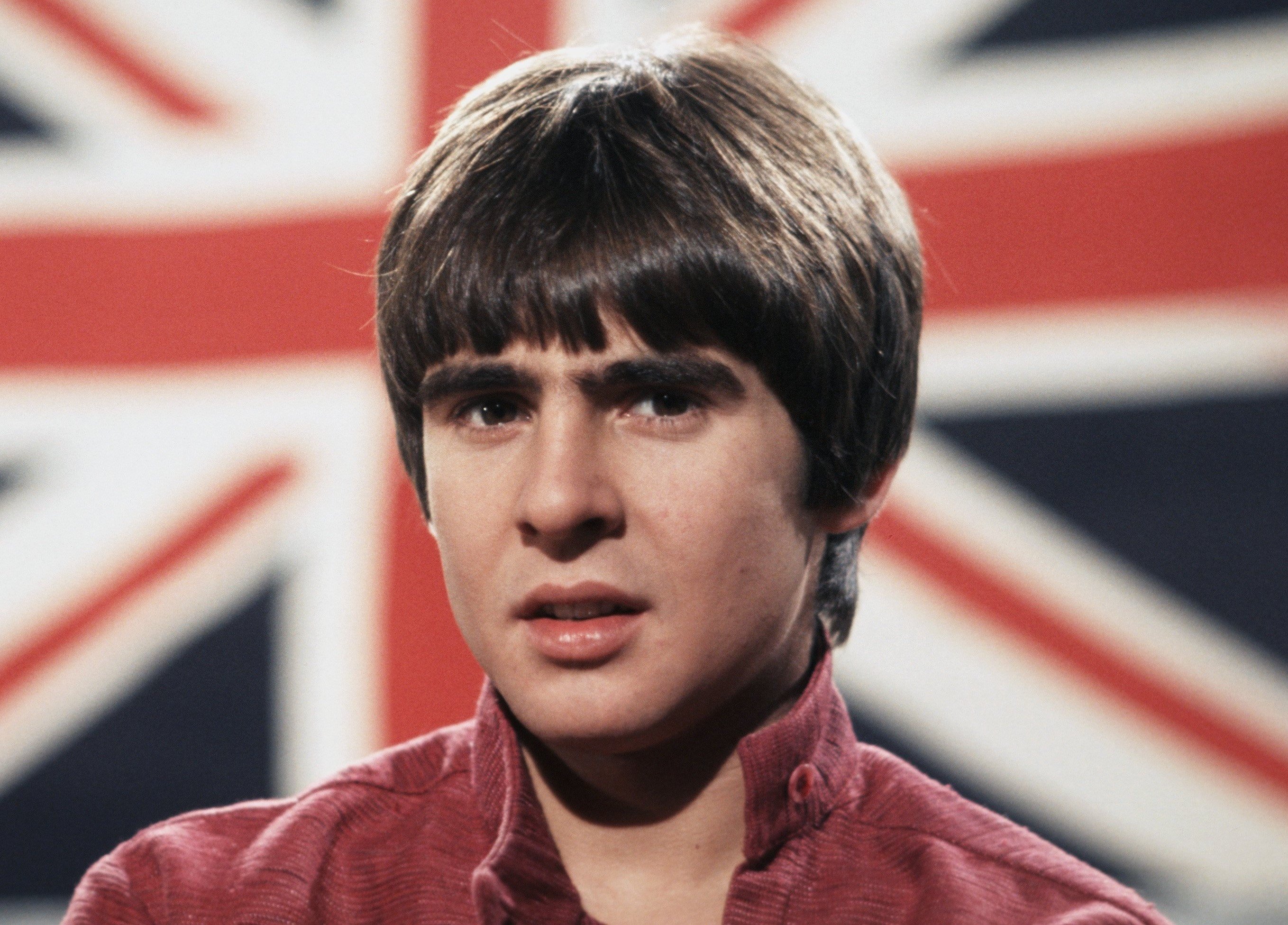 Davy Jones near a flag during The Monkees' "I Wanna Be Free" era