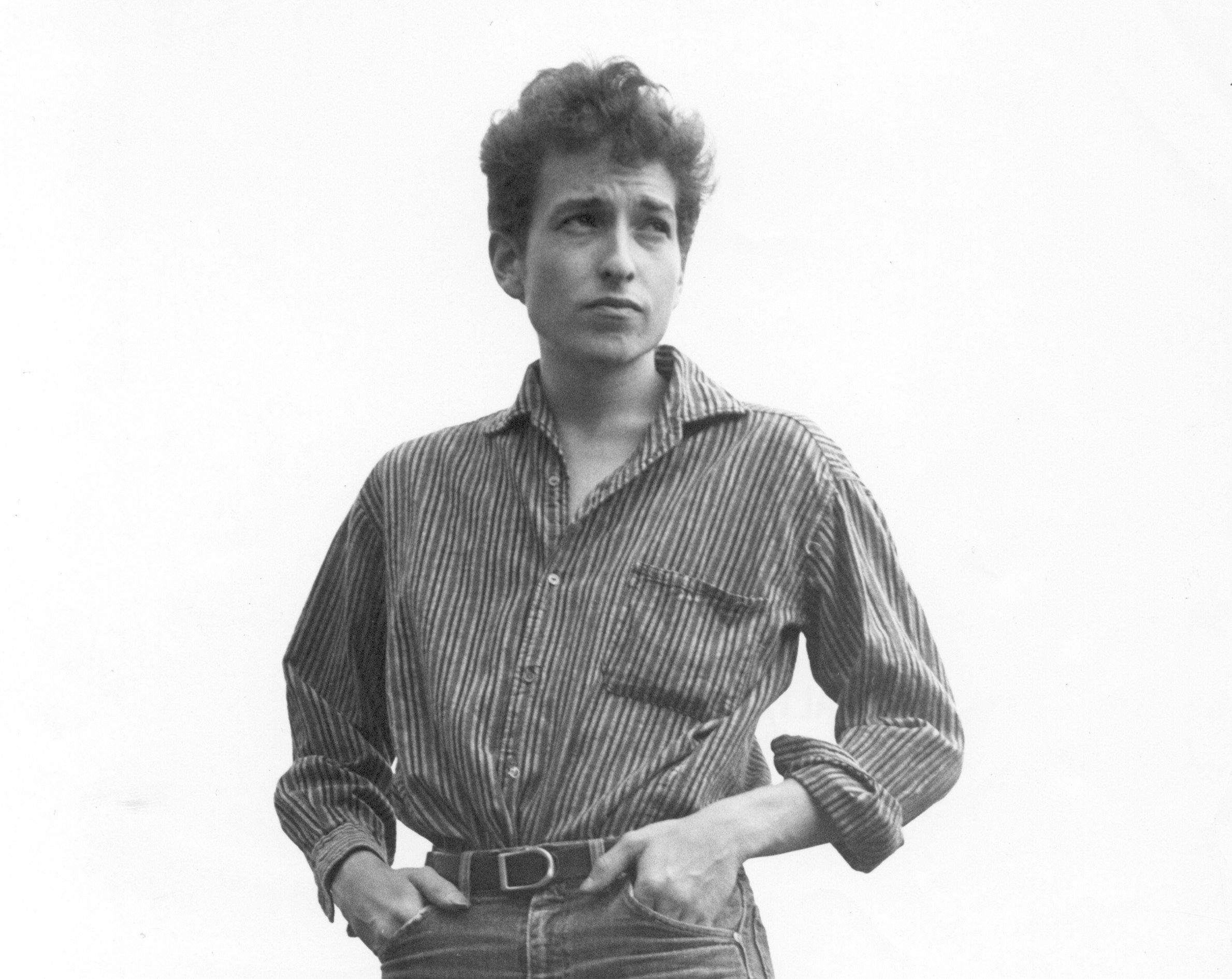 A black and white picture of Bob Dylan standing with his hands on his hips.