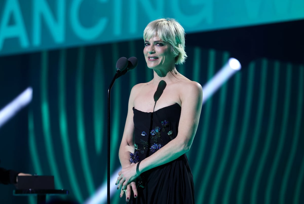 Salma Blair smiles while standing in front of a microphone accepting an award.