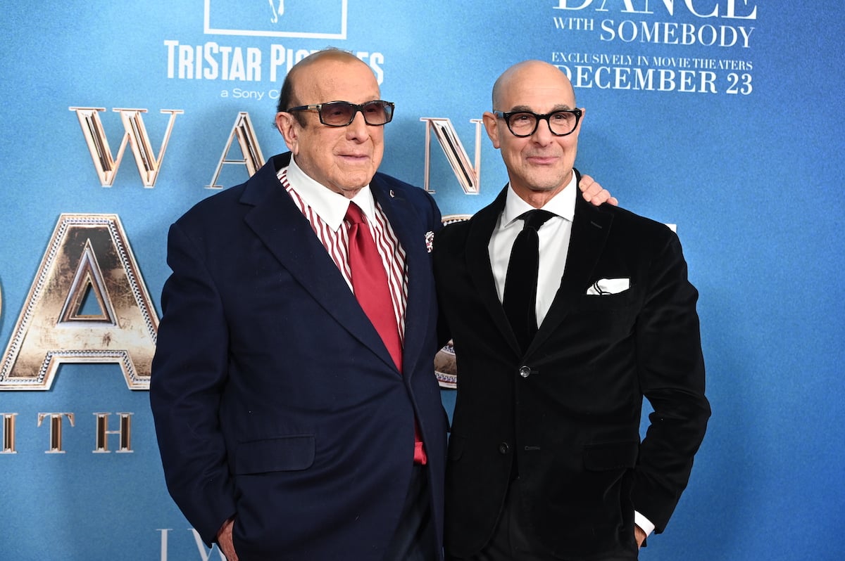 Clive Davis and Stanley Tucci pose for cameras in front of a backdrop featuring the "I Wanna Dance With Somebody" film logo.