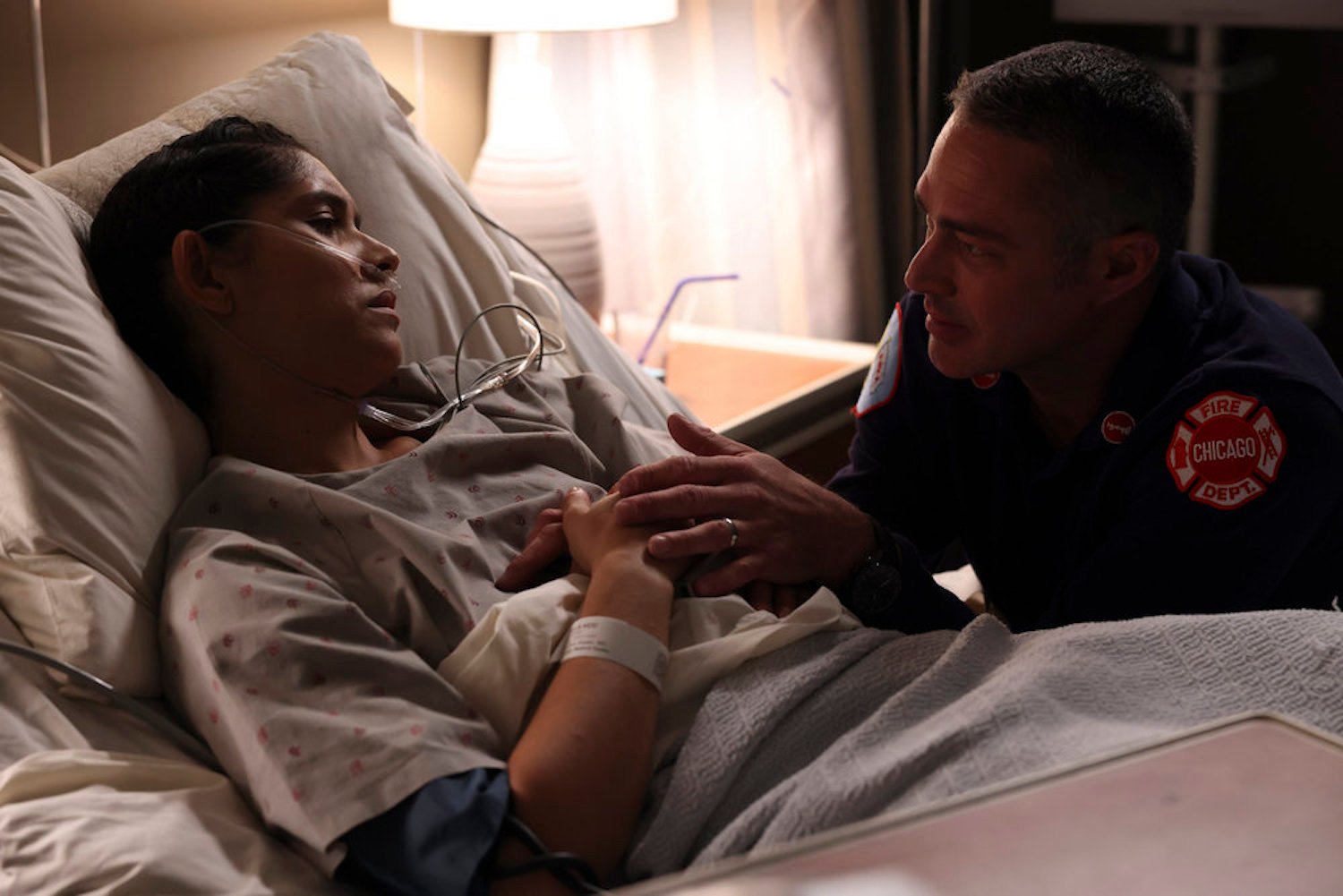 Stella Kidd lying in a hospital bed with Kelly Severide comforting her in 'Chicago Fire' Season 11