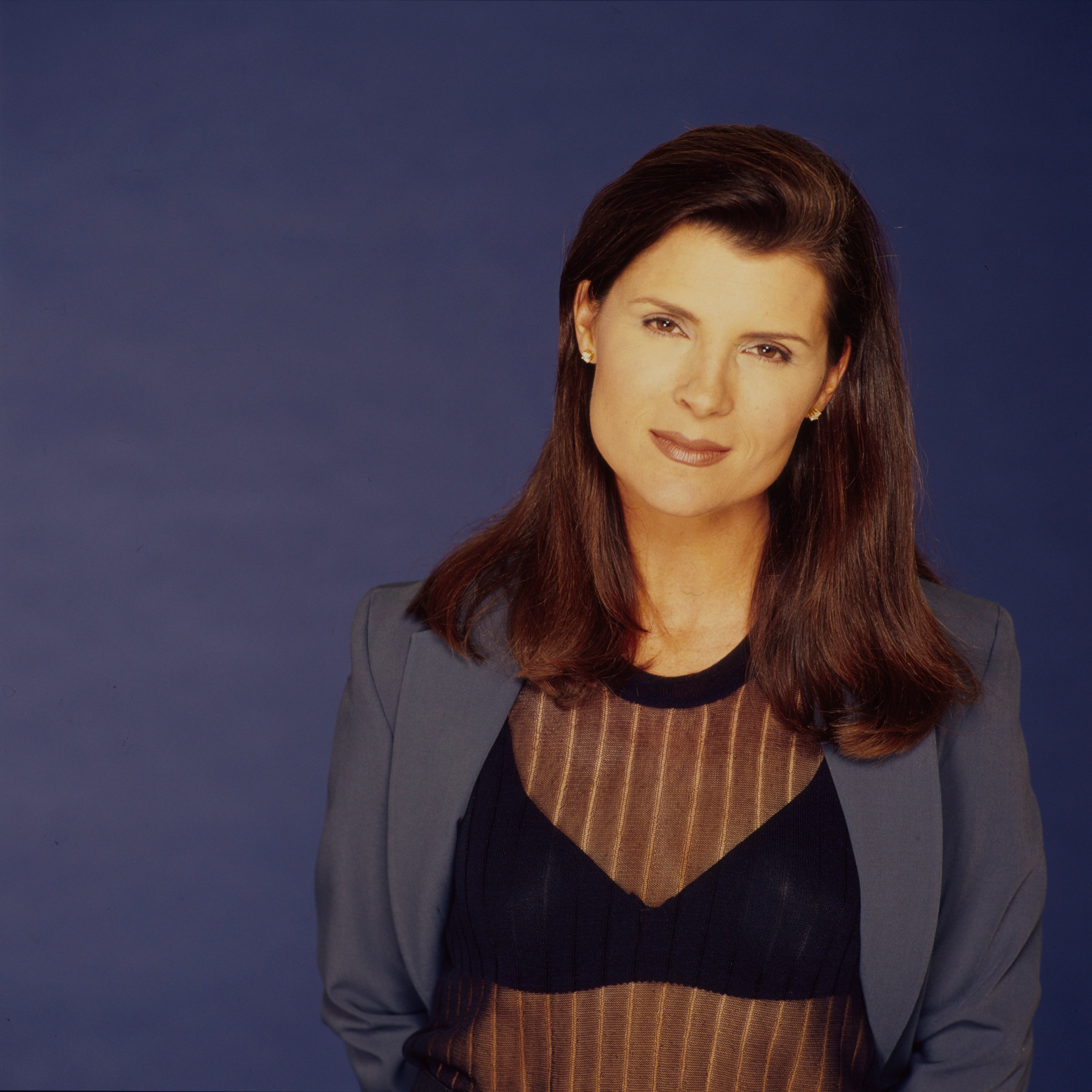 'The Bold and the Beautiful' star Kimberlin Brown in a blue suit, poses in front of a blue backdrop.