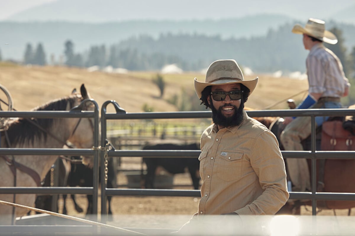 Will Colby and Teeter break up in Yellowstone. Colby walks through the ranch wearing a beige shirt, cowboy hat, and sunglasses. 