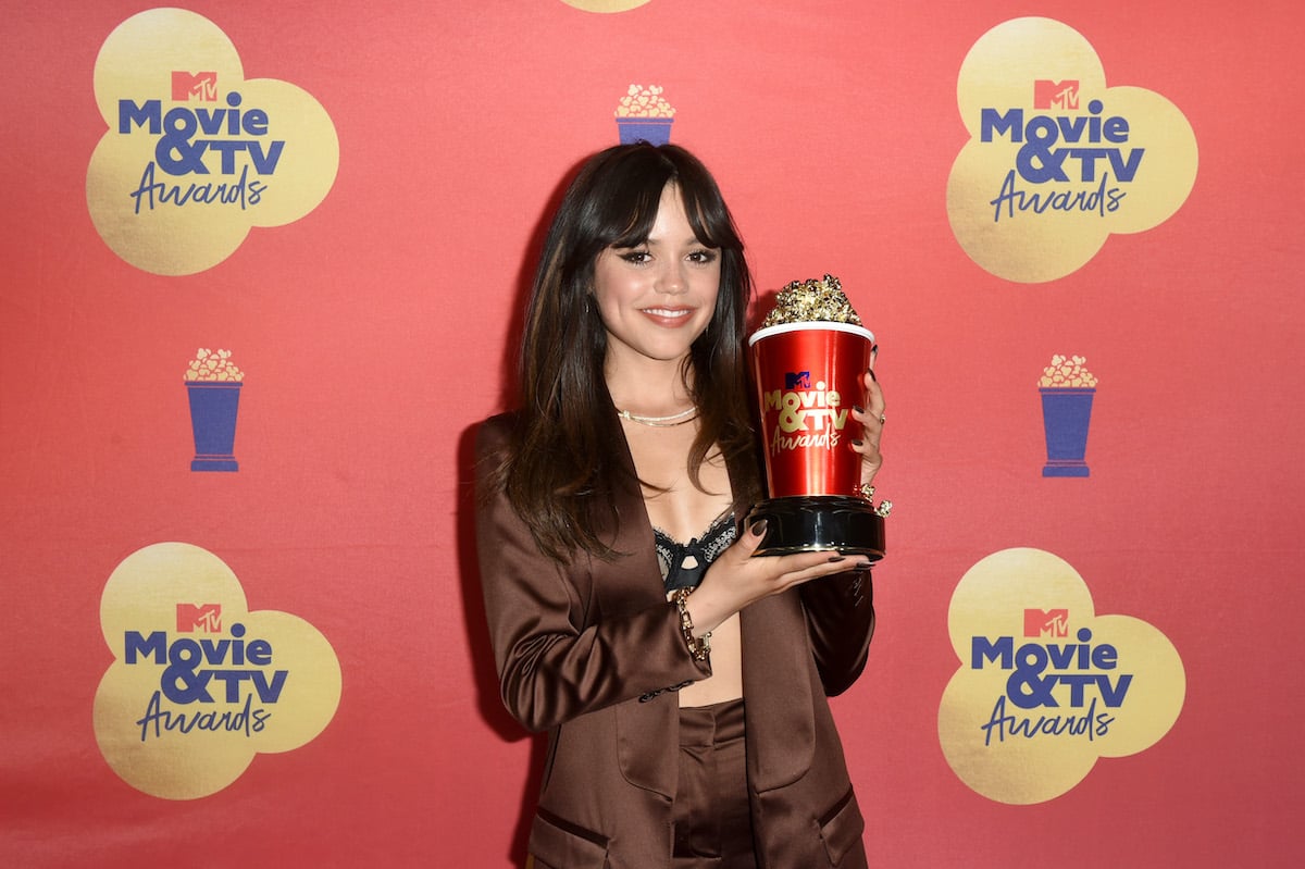 audition guru Jenna Ortega dressed in a brown suit holding a MTV movie award shaped like popcorn