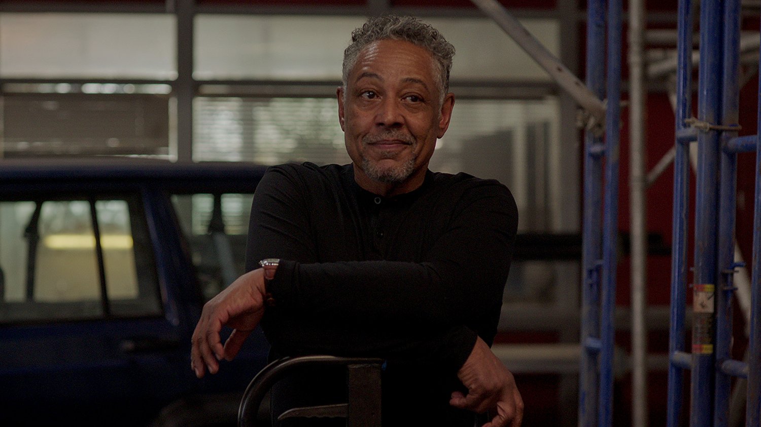 Kaleidoscope Season 1: Giancarlo Esposito as Leo Pap sitting with his arms stacked and a smirk on his face.