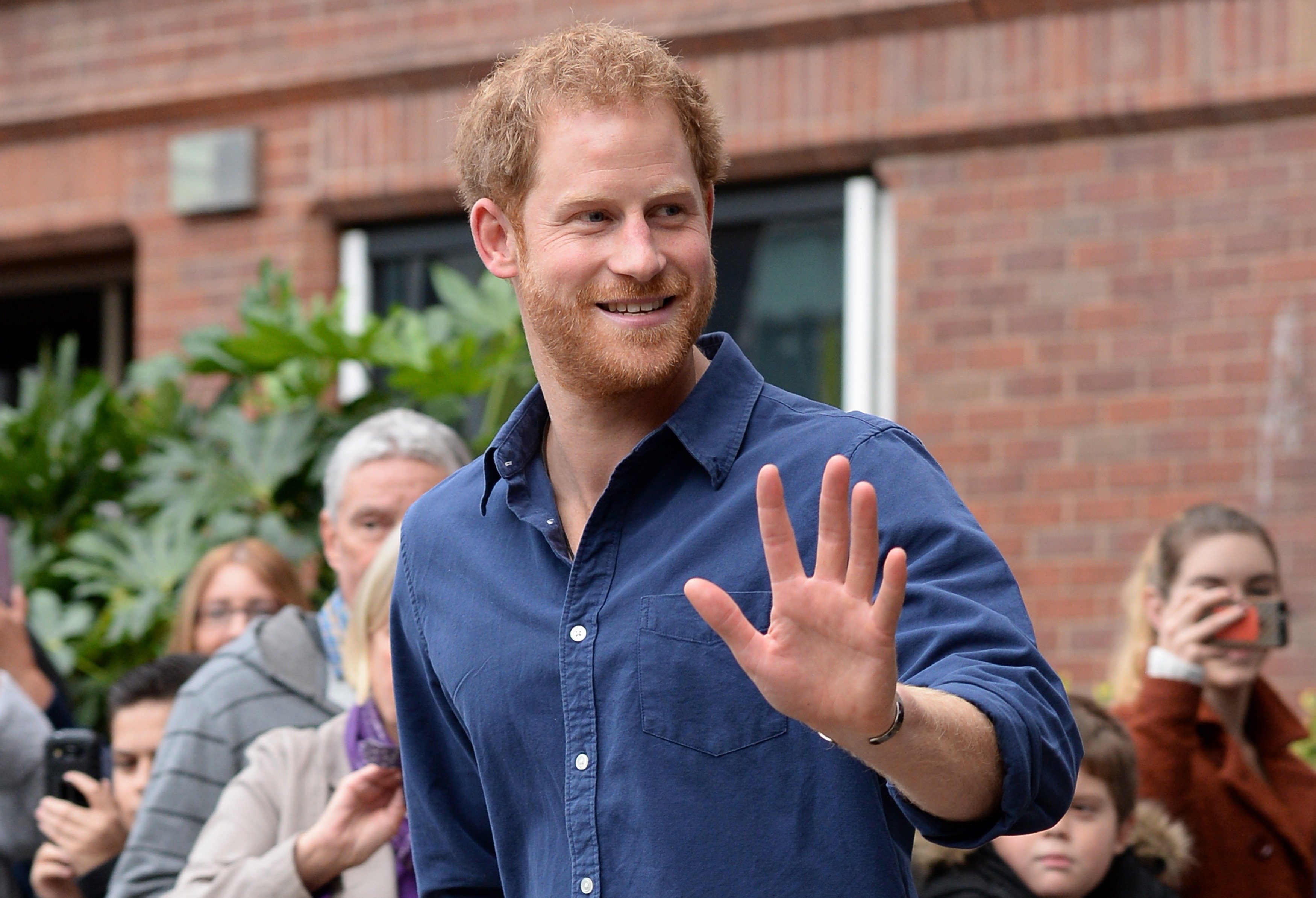 Prince Harry waves to the crowd and smiles. 