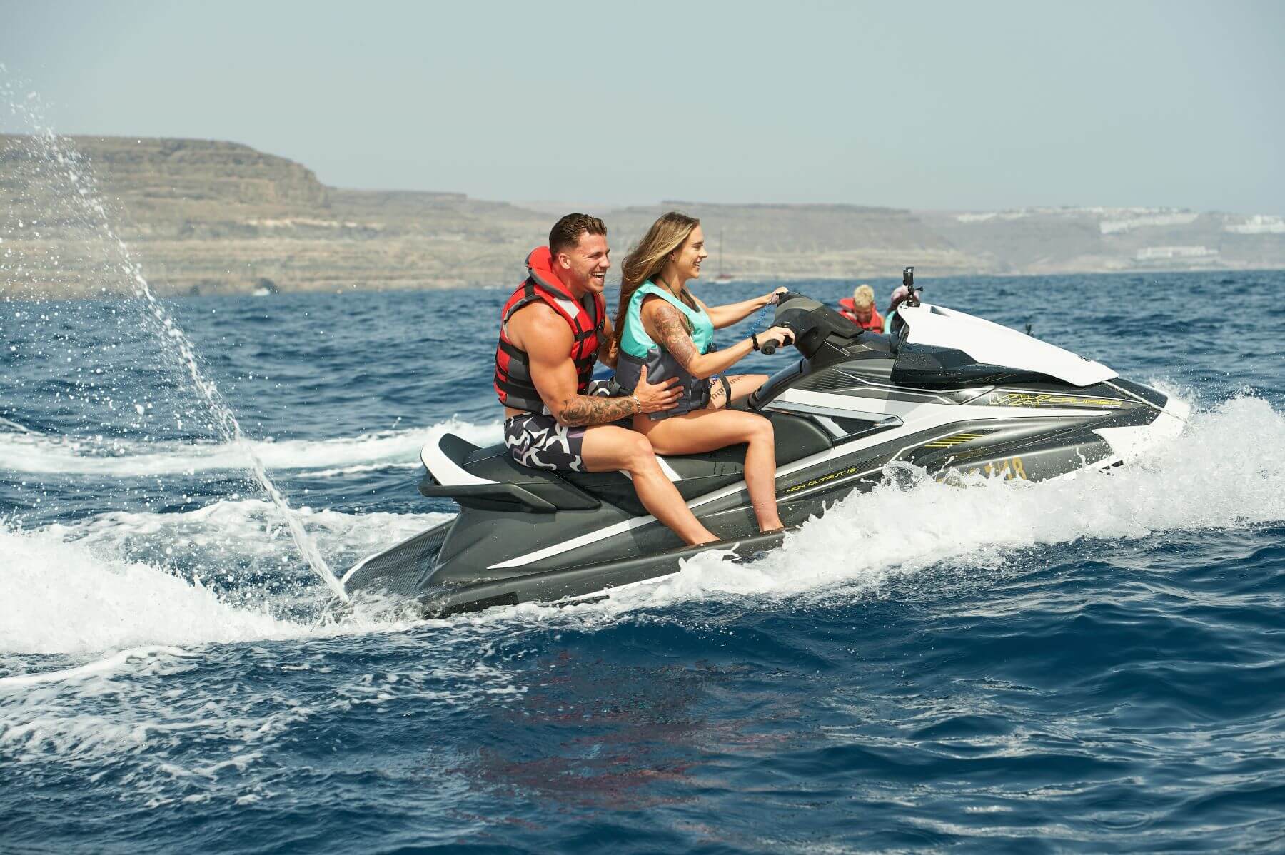 Will Gagnon and Courtney Rowe ride a jet ski in 'Are You the One?' Season 9 on Paramount+. Will wears a red and gray life jacket, and Courtney wears a blue and gray life jacket.